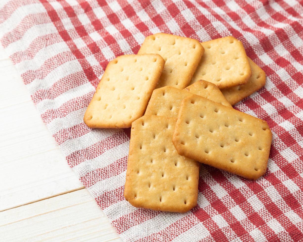 Cracker cookies with tablecloth on white wooden table background photo
