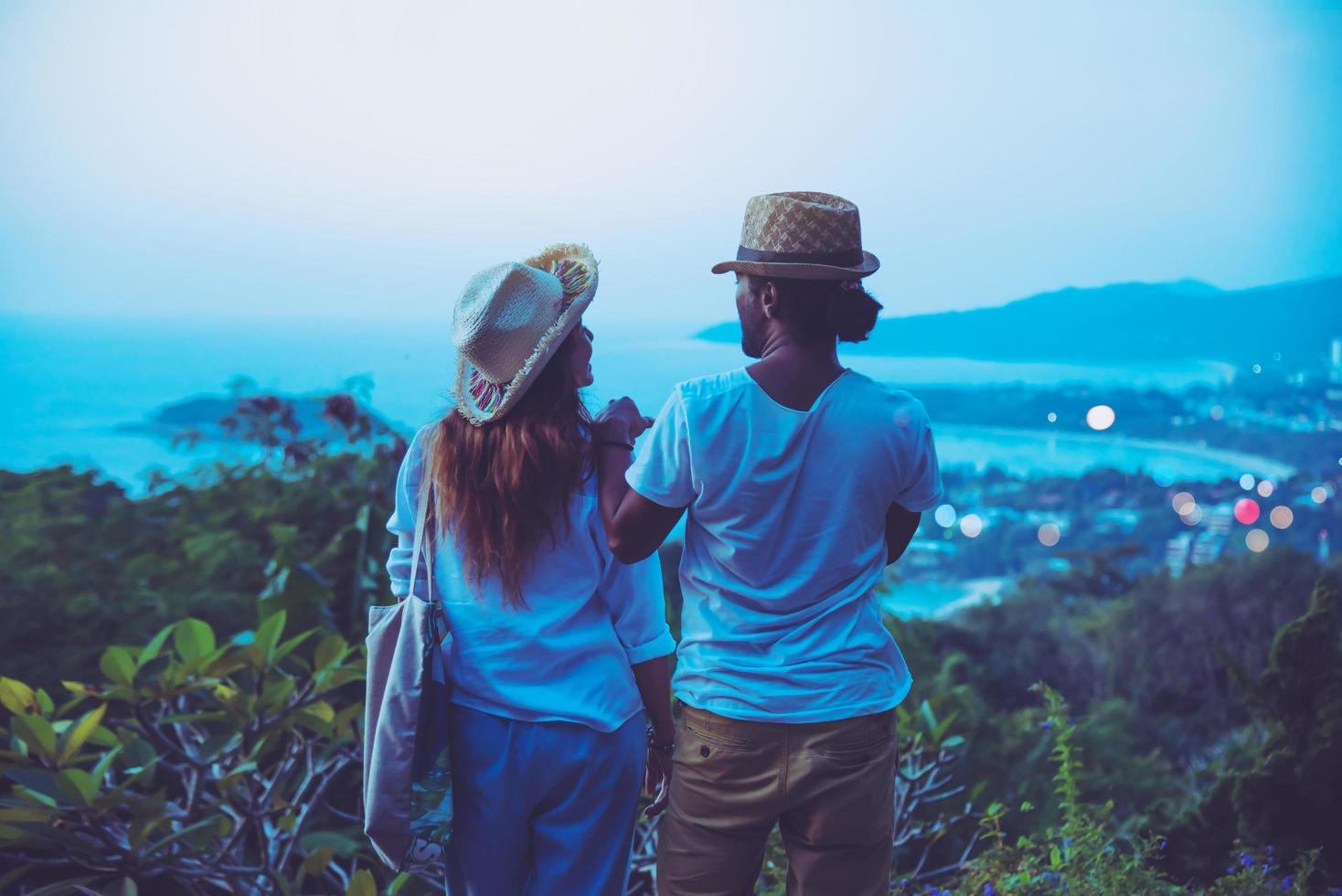 Viajar pareja romántica feliz de mediana edad relajarse en la playa en las vacaciones y de pie mirando la puesta de sol. en verano foto