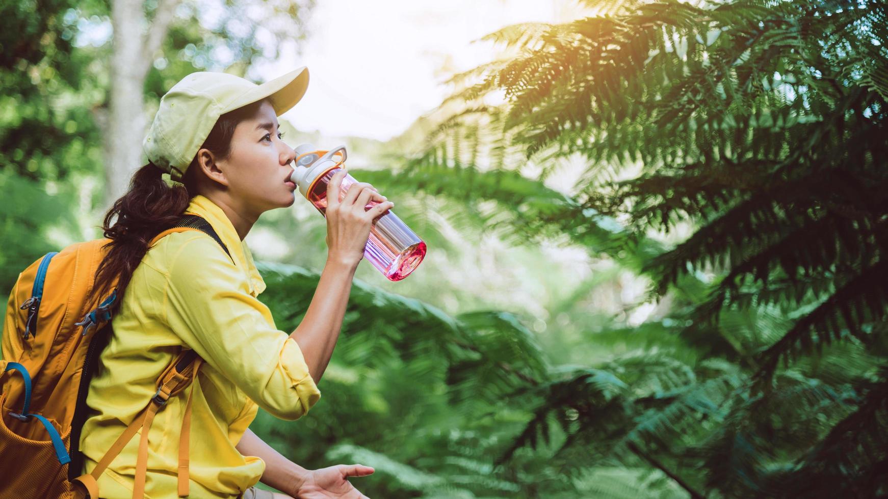 la joven viaja grabando y estudiando la naturaleza del bosque. ella está sentada, relajándose y bebiendo agua. foto