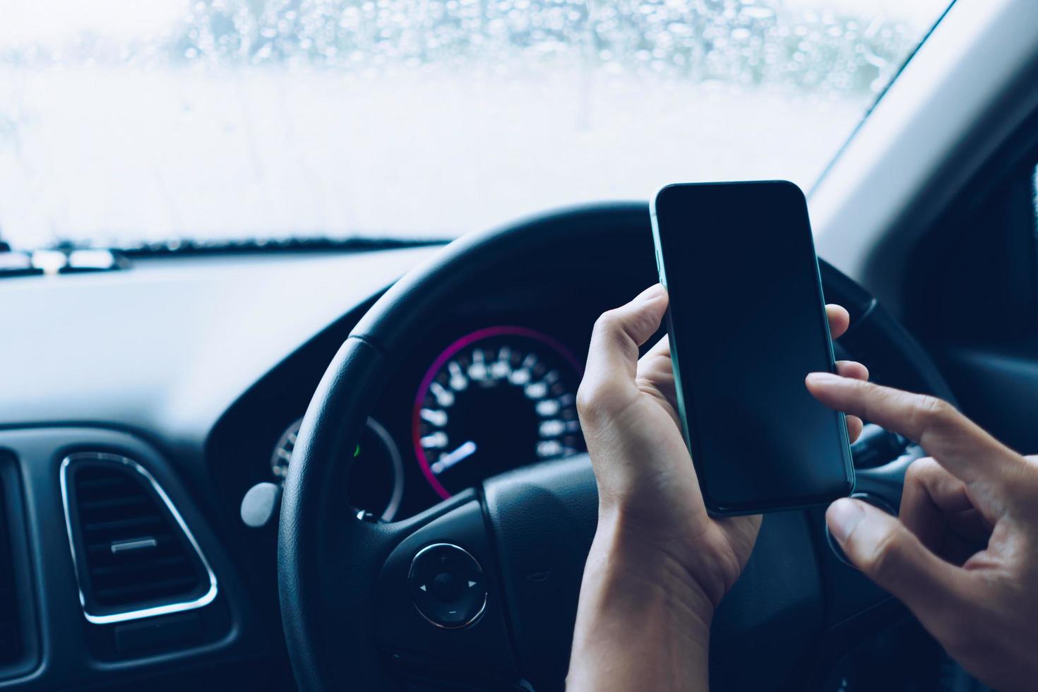 Hand of woman on steering wheel drive a car while using smartphone. photo