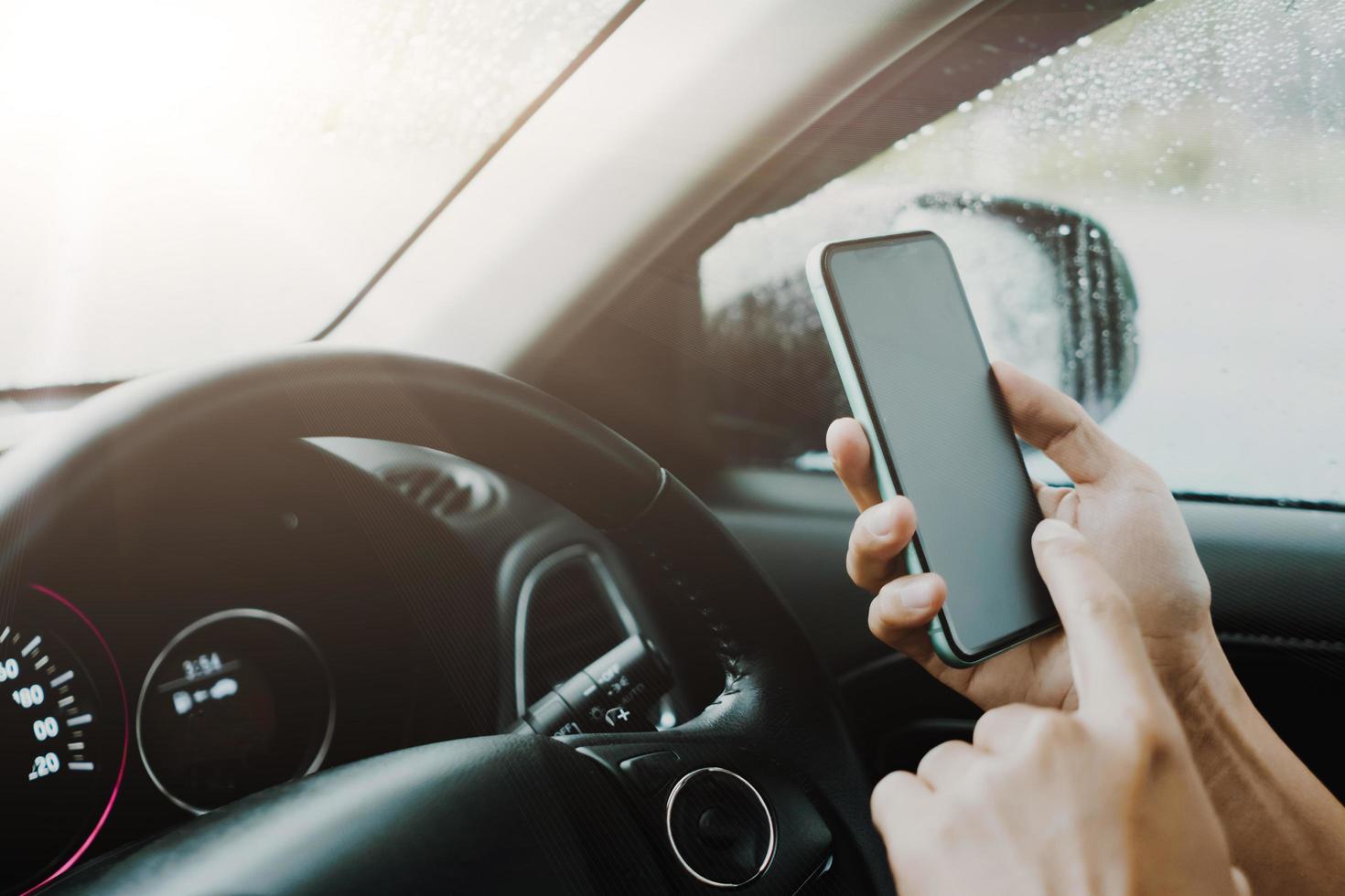 mano de mujer en el volante conducir un coche mientras usa el teléfono inteligente. foto