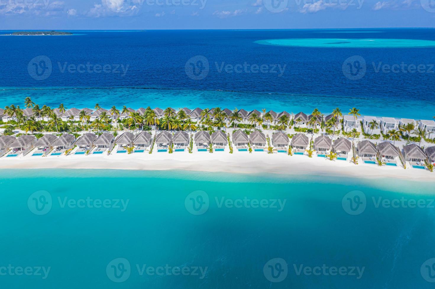 Aerial view of Maldives island, luxury water villas resort and wooden pier. Stunning sky and ocean lagoon beach. Summer vacation holiday and travel concept. Paradise aerial landscape panorama photo