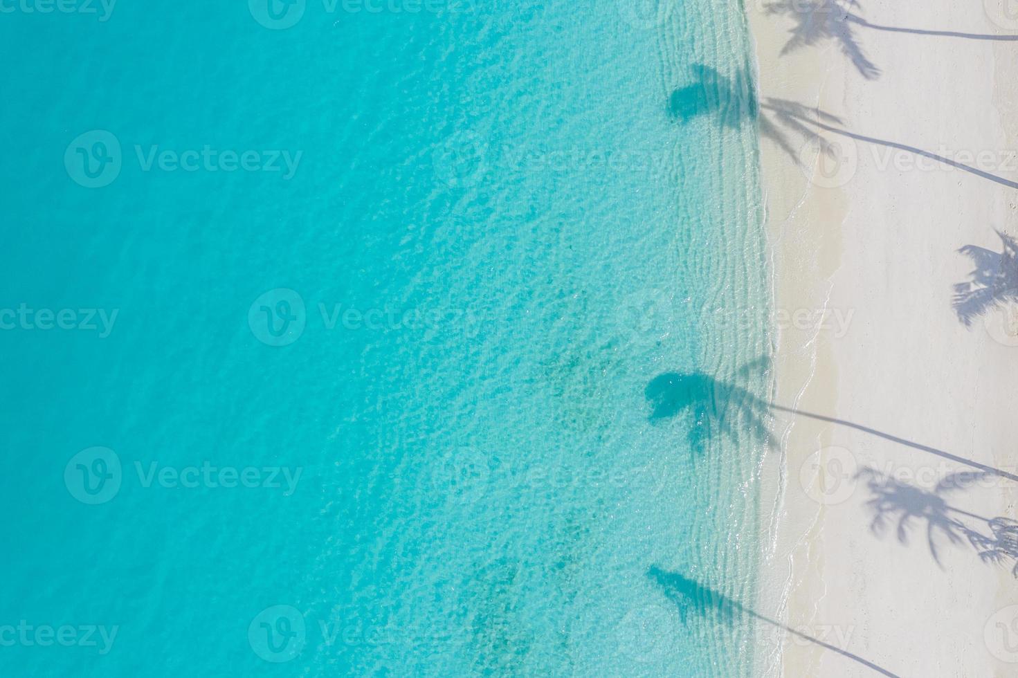 paisaje de playa aérea. Vista de la playa minimalista desde un avión no tripulado o un avión, sombras de palmeras en la arena blanca cerca del mar azul con hermosas ondulaciones y olas. banner de paisaje de playa de verano perfecto. exótico mar azul foto