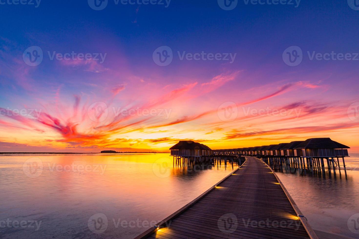 puesta de sol en la isla de maldivas, resort de villas de agua de lujo y muelle de madera. Hermoso cielo y nubes y fondo de playa para vacaciones de verano y concepto de viaje foto