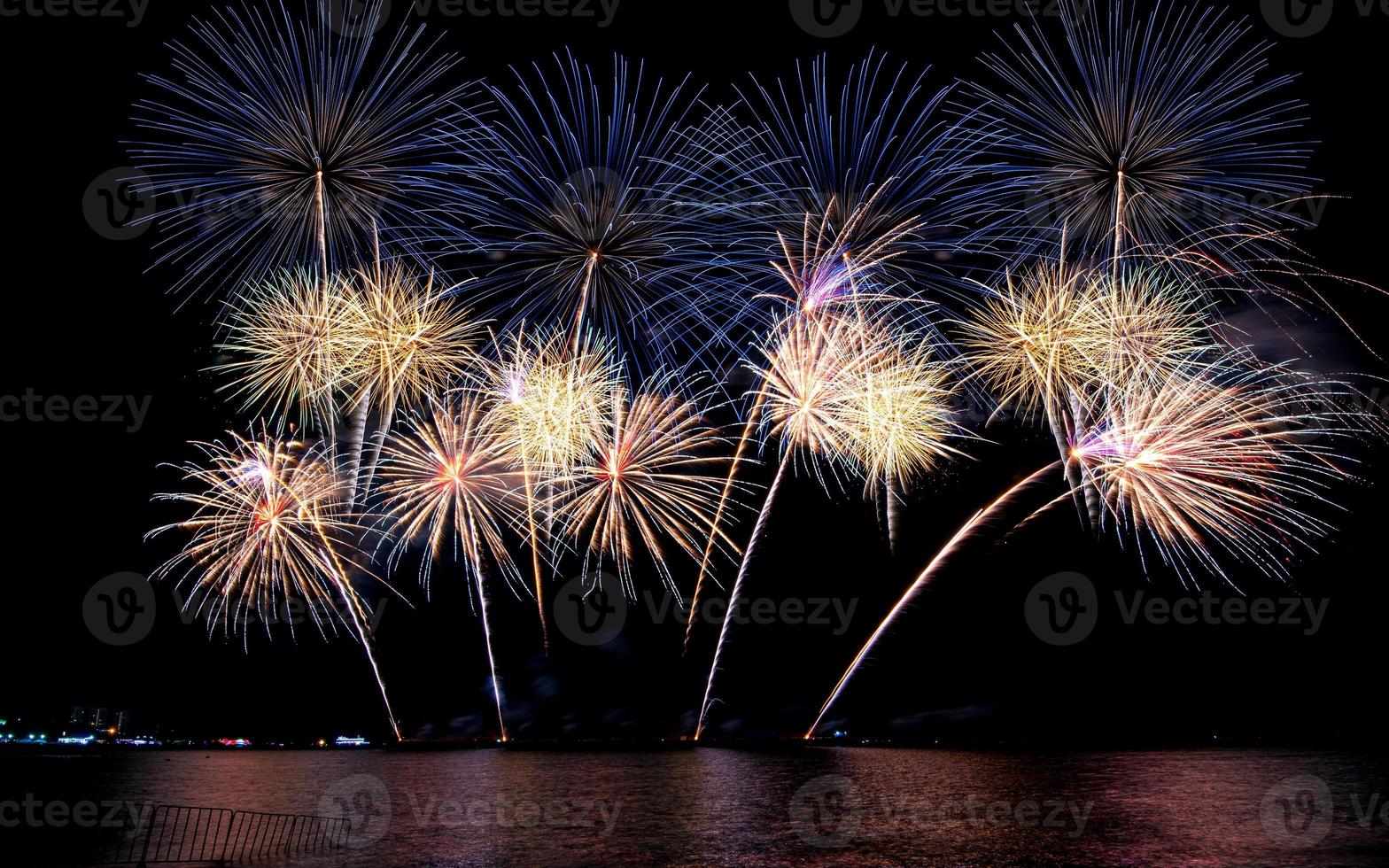 Increíble y hermoso colorido espectáculo de fuegos artificiales en la noche de celebración, que se muestra en la playa del mar con reflejos multicolores sobre el agua foto