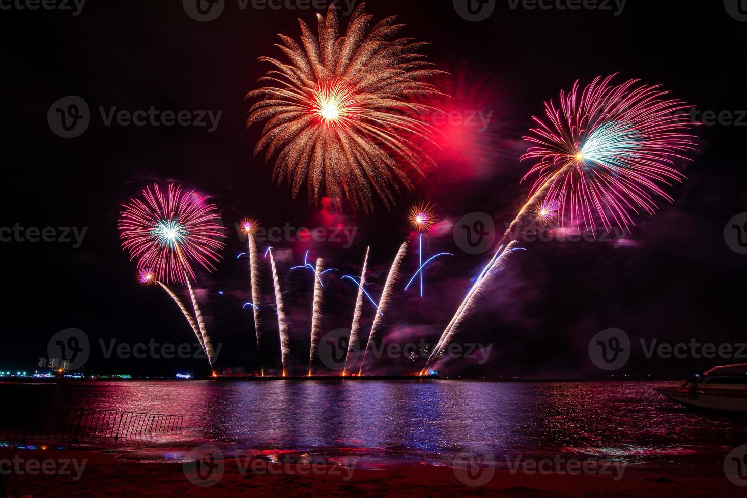 Amazing beautiful colorful fireworks display on celebration night, showing on the sea beach with multi color of reflection on water photo