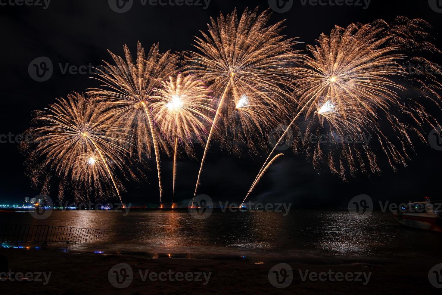 Increíble y hermoso colorido espectáculo de fuegos artificiales en la noche de celebración, que se muestra en la playa del mar con reflejos multicolores sobre el agua foto