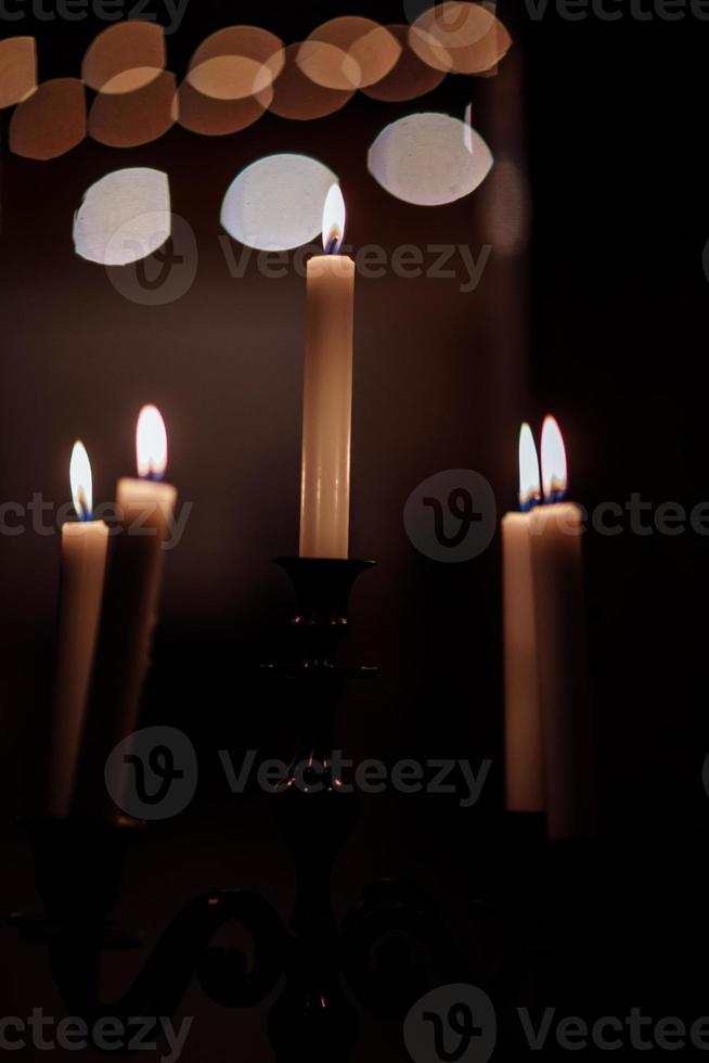 Burning candles on bronze candlestick against dark background at home.candles in the interior. Vintage style. Calm romantic atmosphere. Horizontal image for design. photo