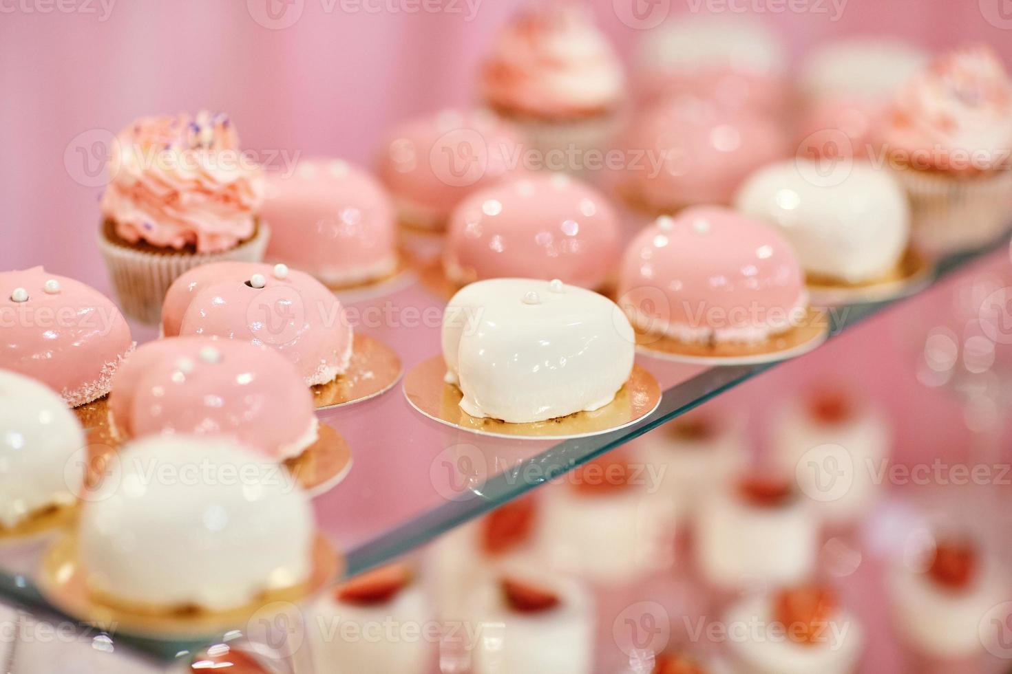 Wedding candy bar with pink and white deserts. Strawberry cupcakes, jelly and modern desserts. photo