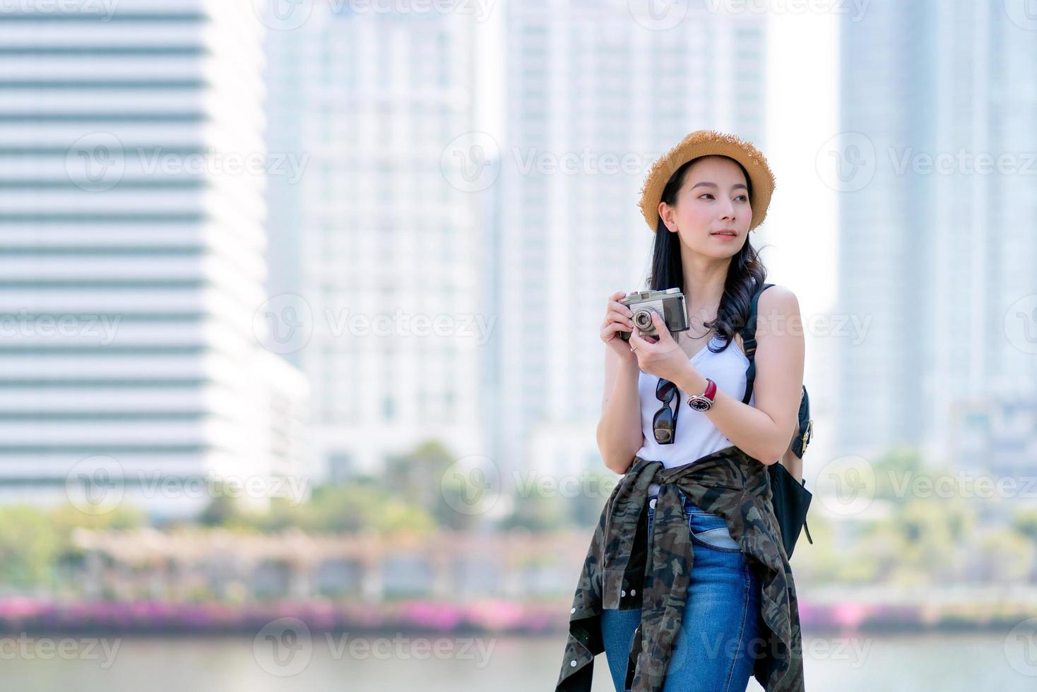 Beautiful asian tourist woman enjoy taking photo by retro camera at tourist sightseeing spot. Vacation travel in summer.