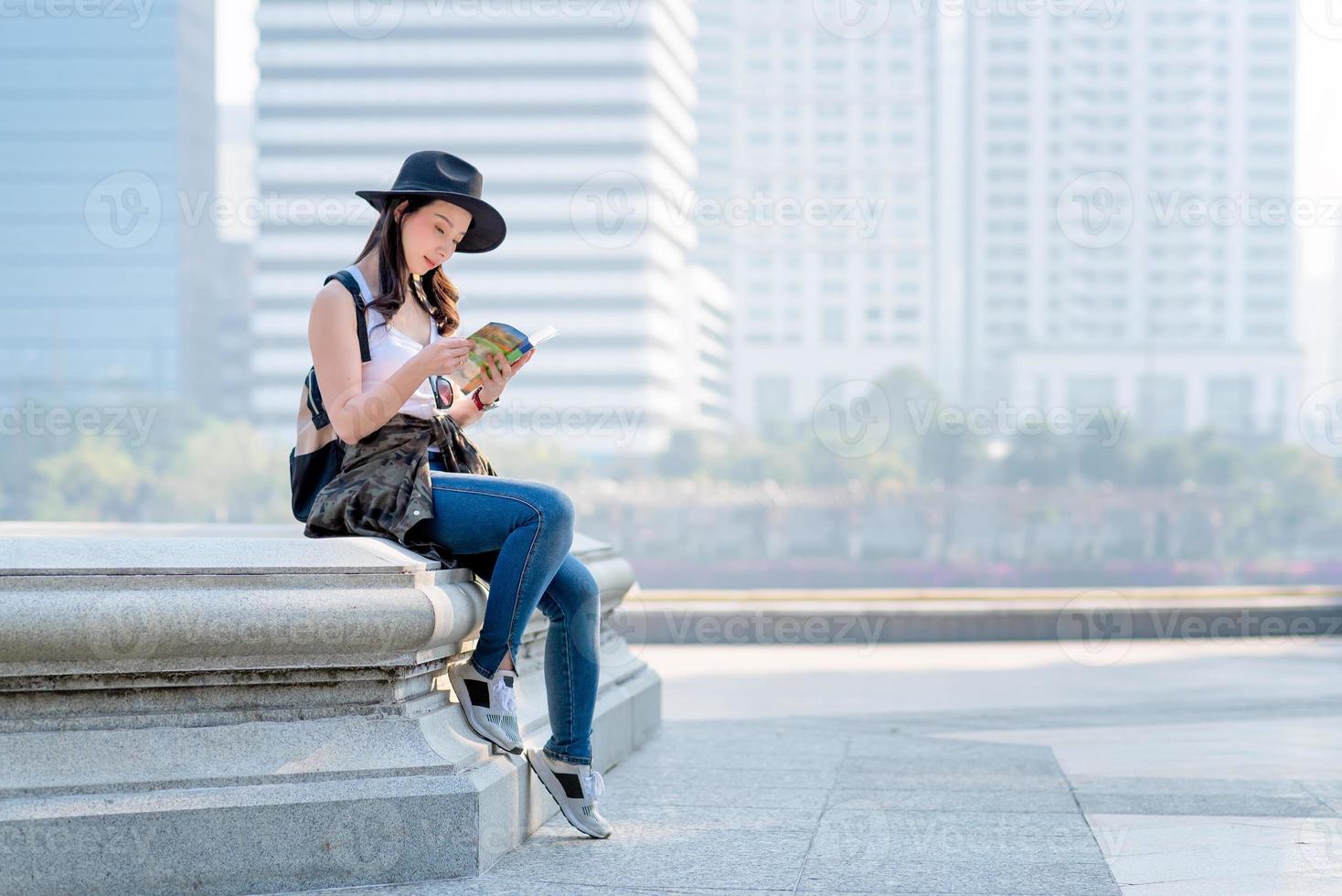 Hermosa mujer turista asiática leyendo la guía de viajes para buscar la ubicación de las visitas turísticas. viajes de vacaciones en verano foto