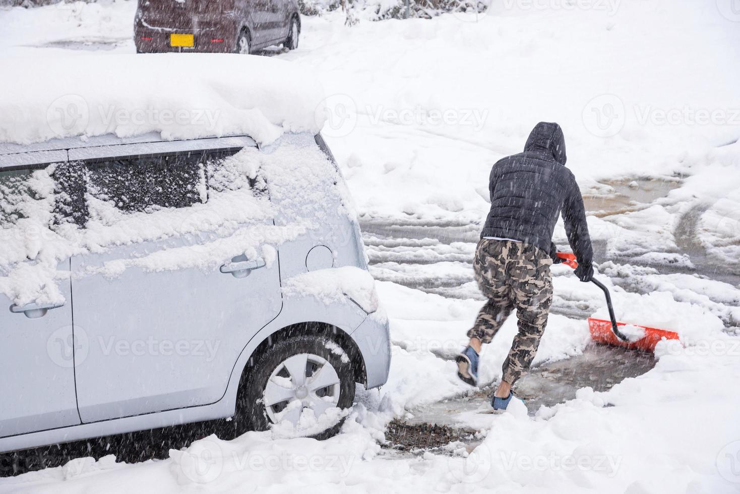 nieve blanca fresca que cae en la carretera y el coche de la cubierta del parque público en la temporada de invierno en kawaguchiko, japón. foto