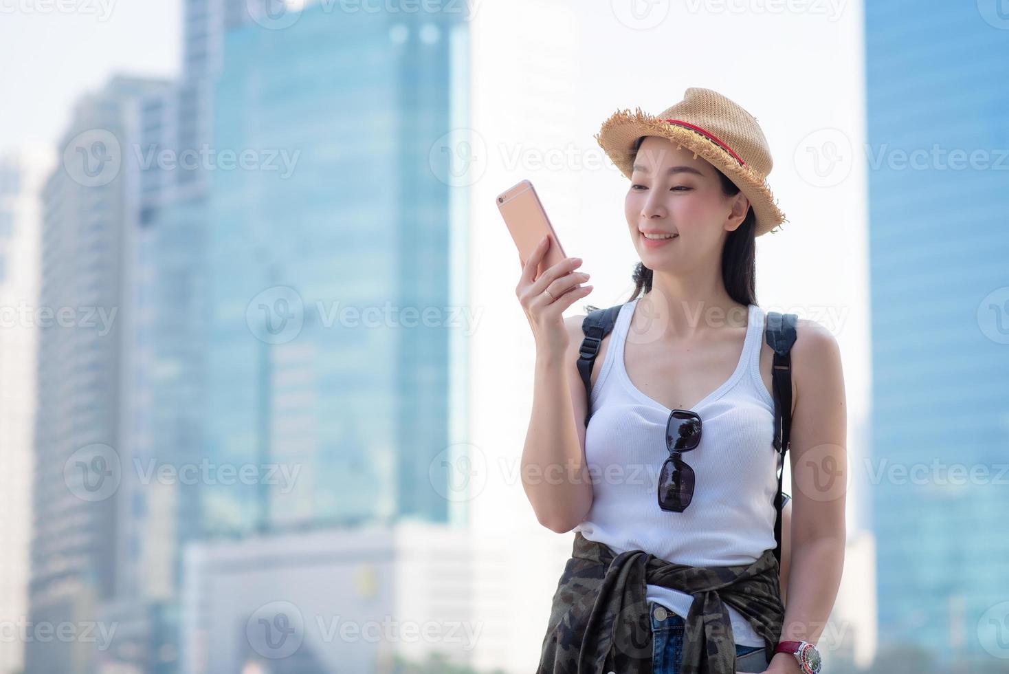 Hermosa mujer turista asiática mirando el teléfono móvil para buscar la ubicación del hito. viajes de vacaciones en verano foto