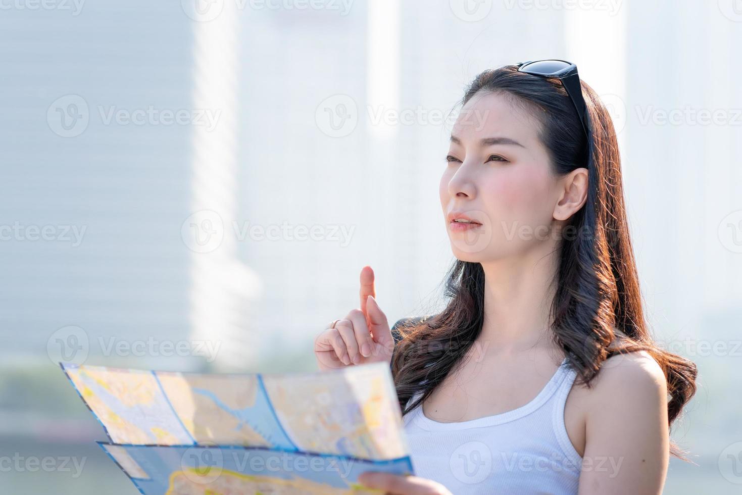 Beautiful asian tourist woman looking at map for searching location of landmark. Vacation travel in summer photo