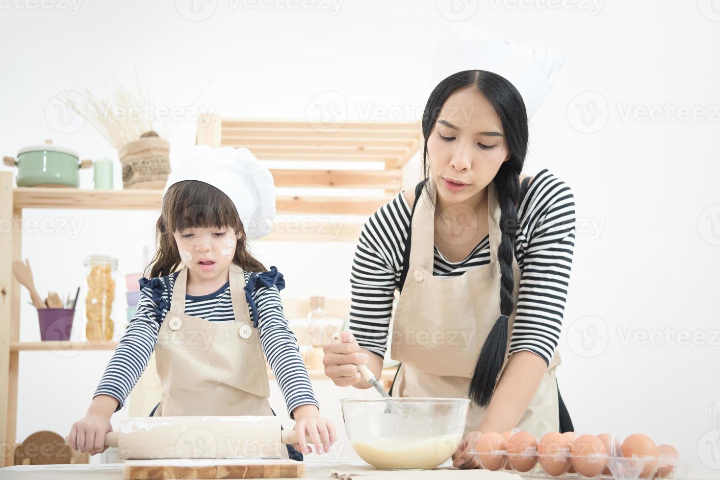Asian mother and her daughter are preparing the dough to make a cake in the kitchen room on vacation.Photo series of Happy family concept. photo