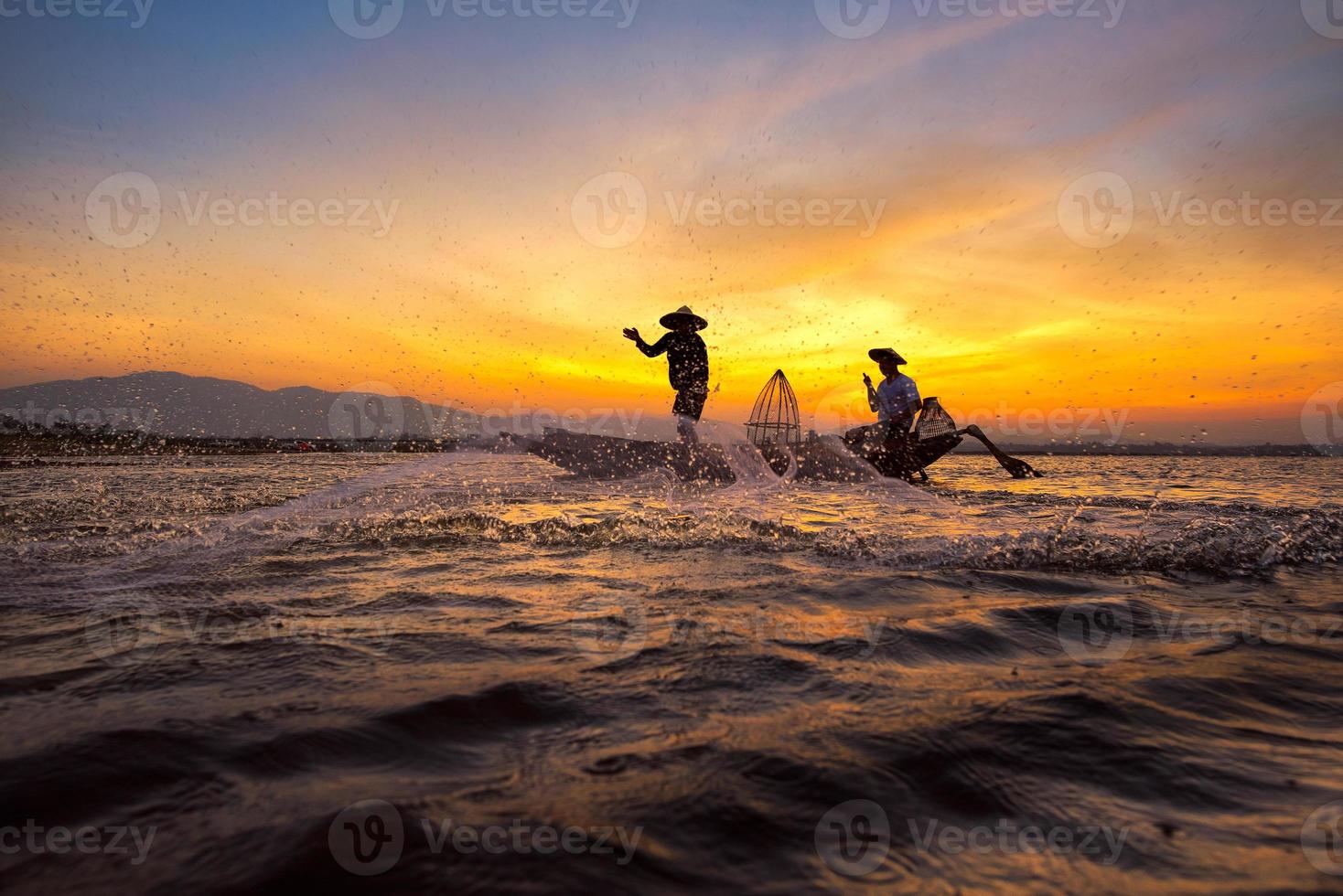 Silueta pescador asiático en bote de madera echando una red para pescar peces de agua dulce en el río de la naturaleza temprano en la mañana antes del amanecer. foto