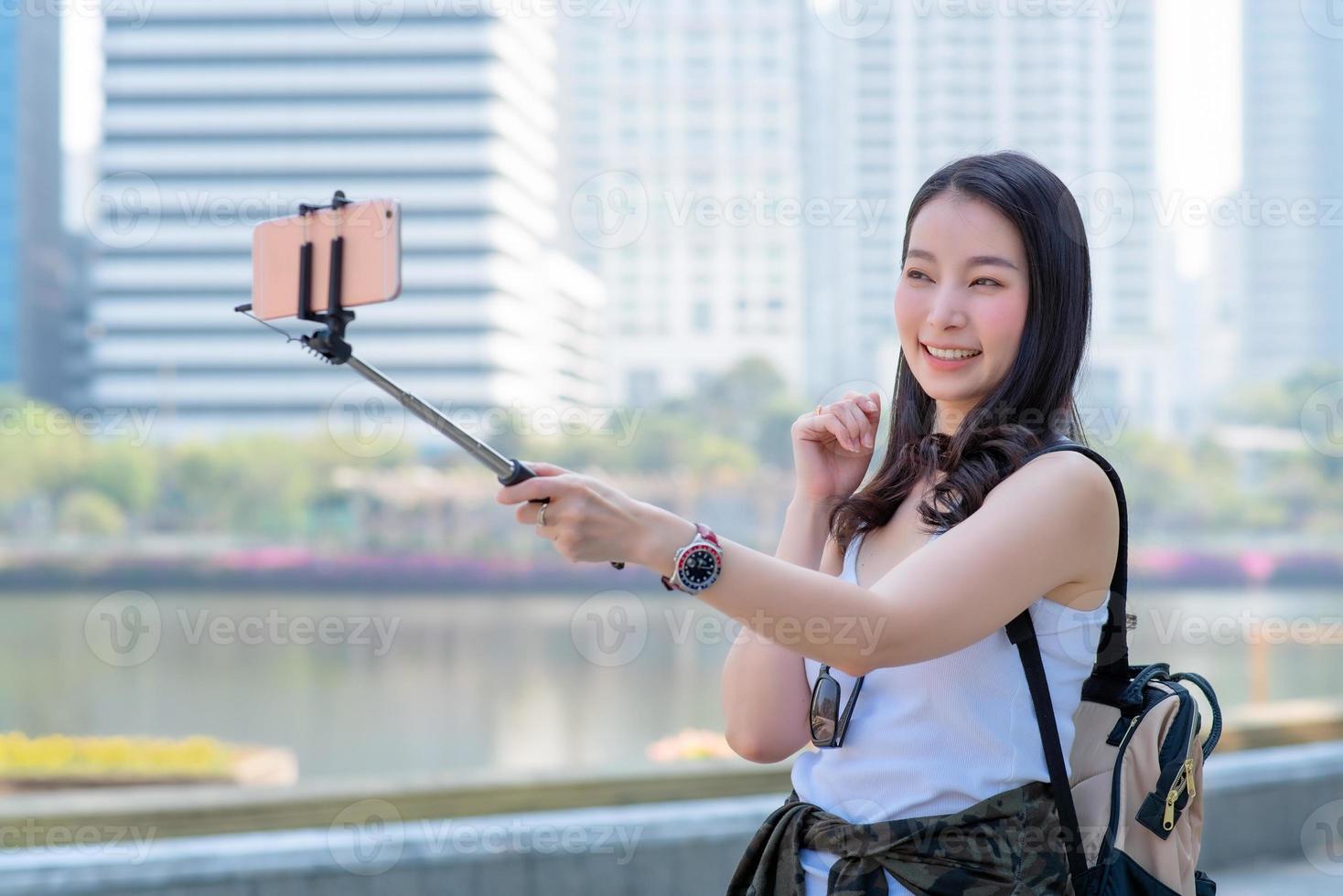 Beautiful asian tourist woman use video call via a smartphone in urban city downtown. Vacation travel in summer. photo