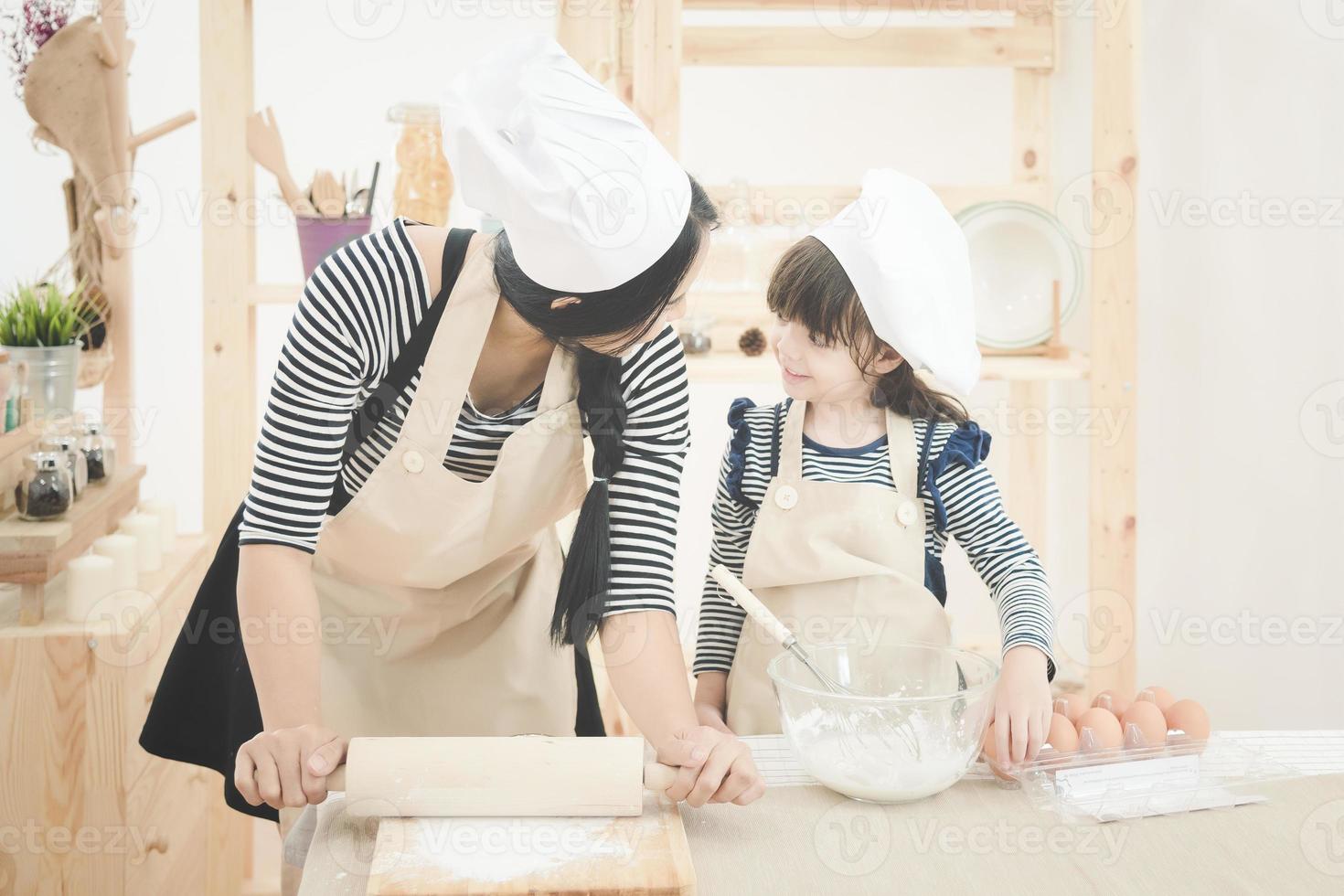 familia feliz en la cocina. Madre asiática y su hija preparando la masa para hacer un pastel.Diseño de foto para la familia, los niños y el concepto de gente feliz.