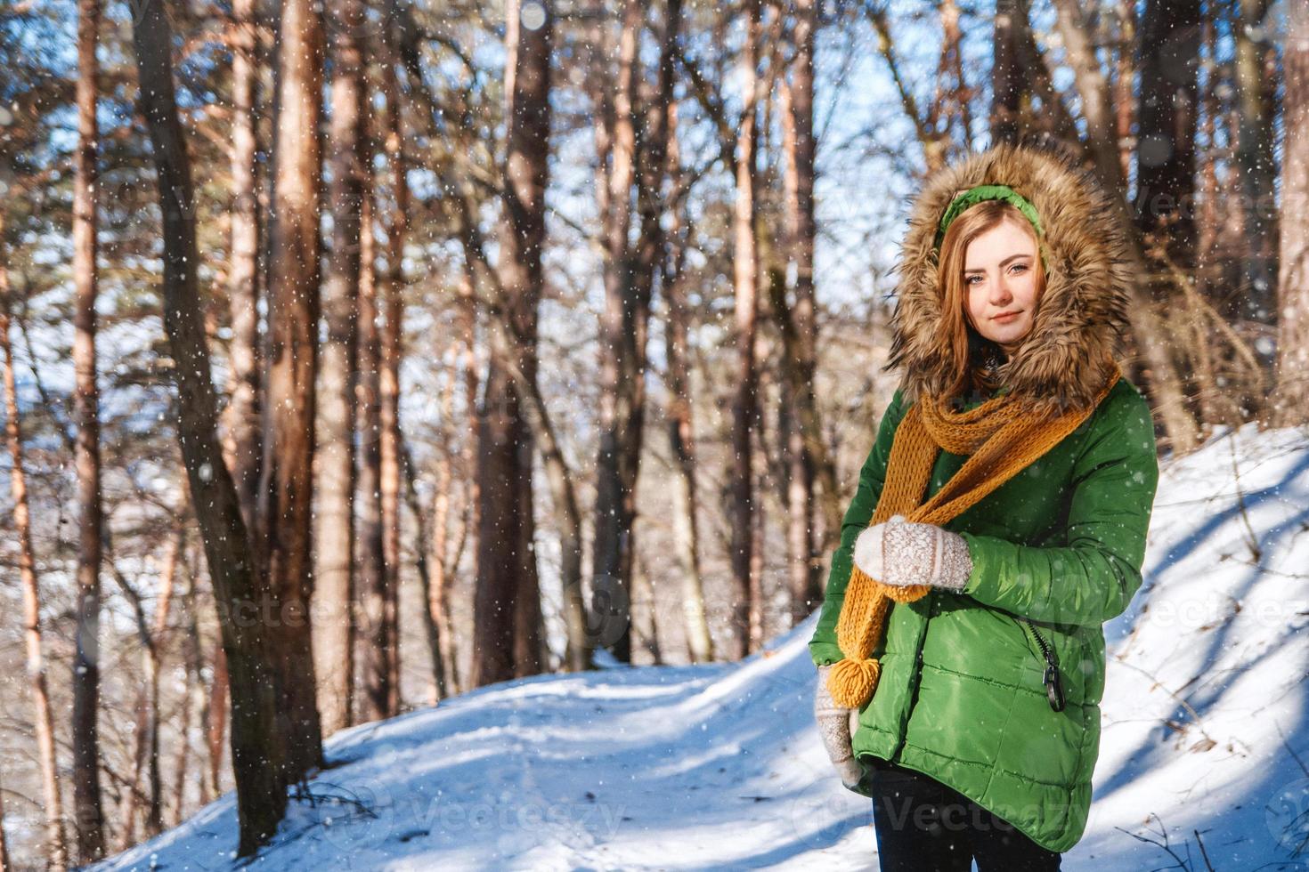 Una niña con un suéter y gafas en invierno en un bosque cubierto de nieve.
