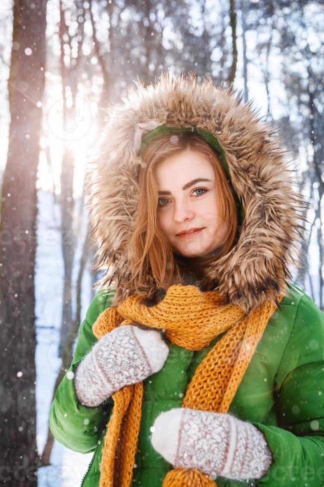 Beautiful young girl in a winter forest. Winter portrait of women dressed in mittens and scarf photo