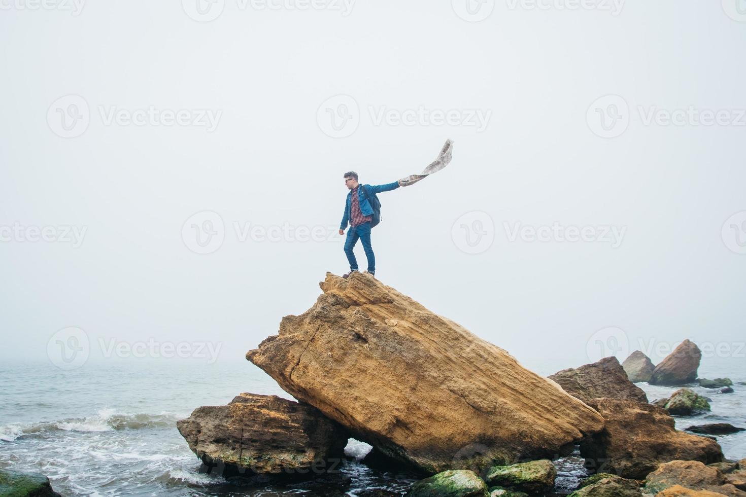 Hombre viajero se encuentra en una roca en el fondo de un hermoso mar foto