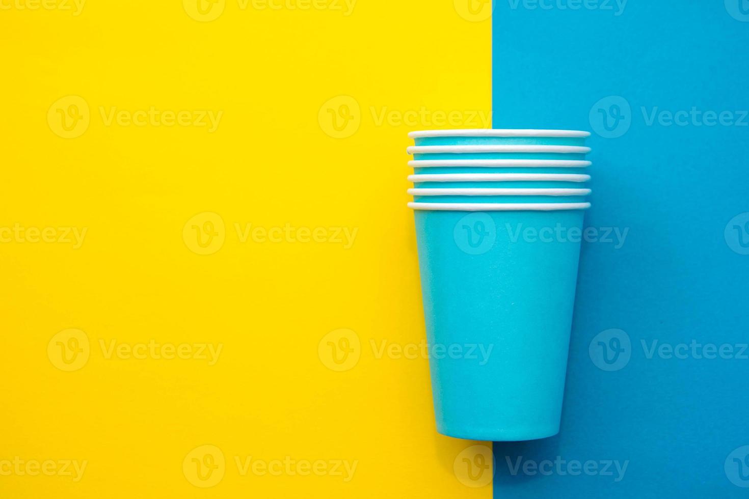 Blue paper disposable cups yellow and blue background. Cooking utensil. Cutlery sign. Top view. Minimalist Style. Copy, empty space for text photo