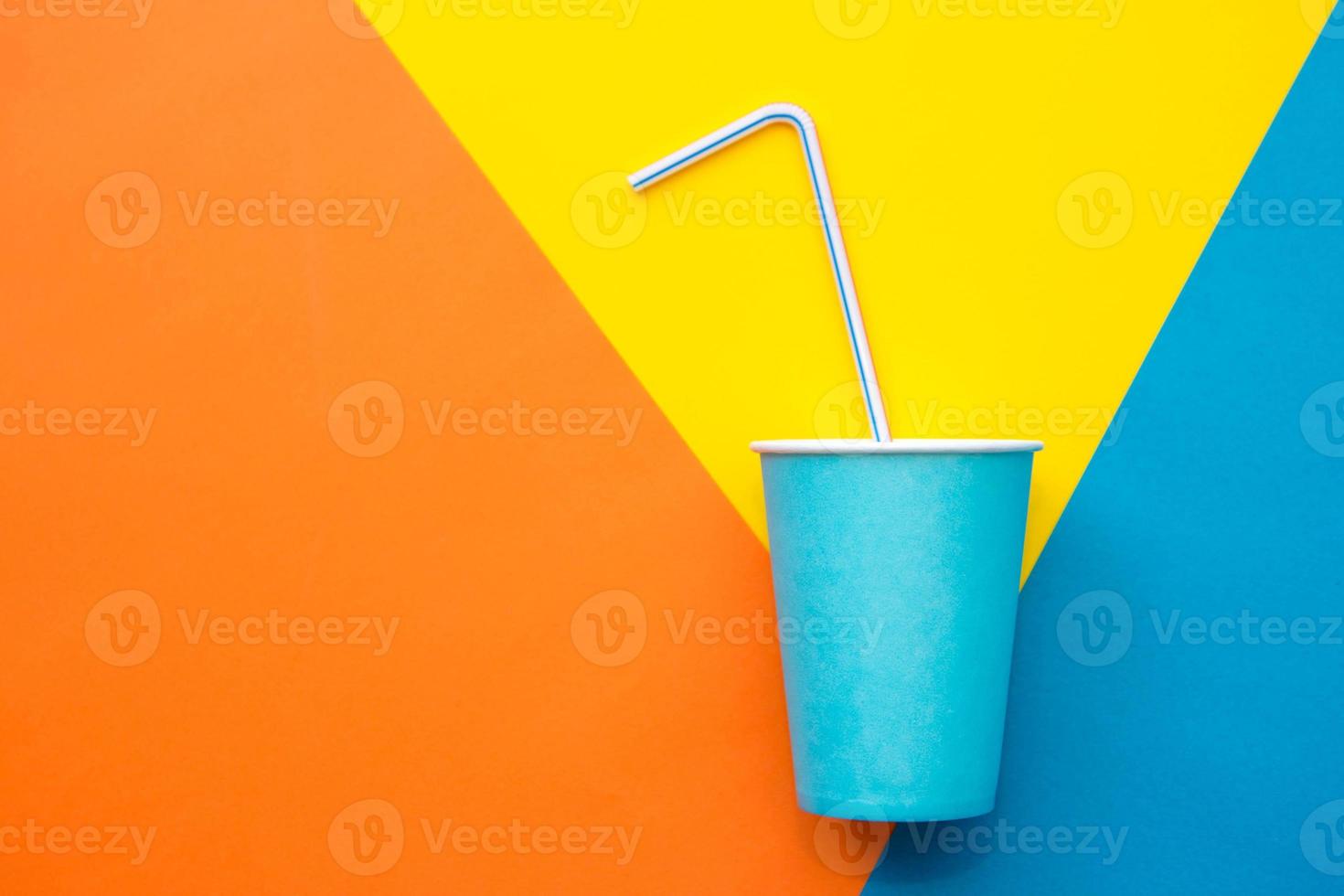 Blue paper cups with drinking colored plastic straws on beautiful multicolored background. Set for party. Top view. Minimalist Style. Copy, empty space for text photo