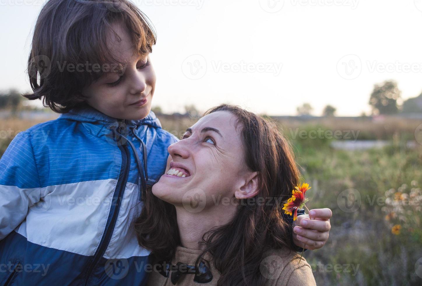 un niño le da una flor a su madre foto