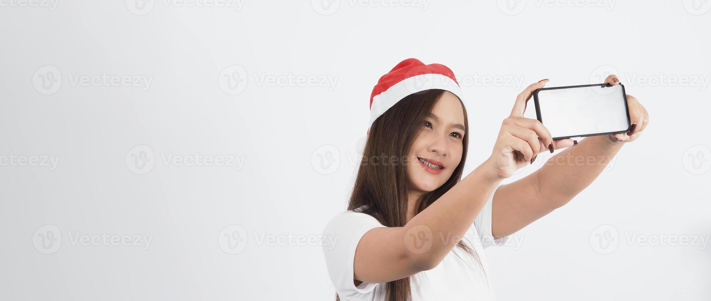 Mujer asiática con smartphone en mano que posa como selfie o videollamada foto