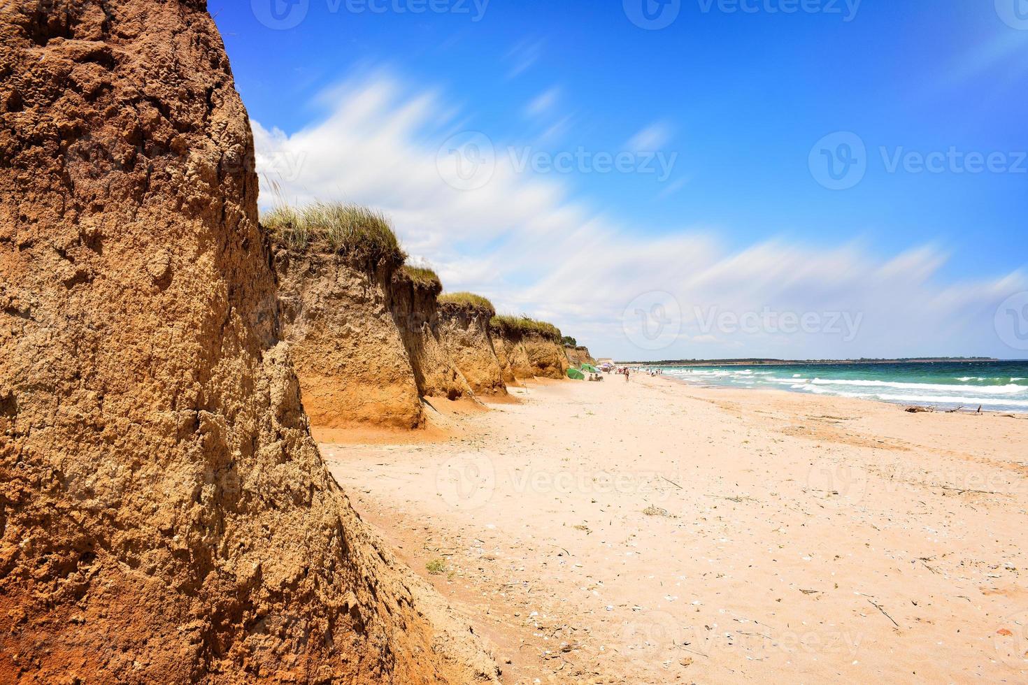 Sunny Bulgarian beach tranquil scene with sand cliffs. Empty coastline on the shore of the Black Sea, Shabla. Perfect place for relaxation on the summer sunny weekends. Clean water and blue sky. photo