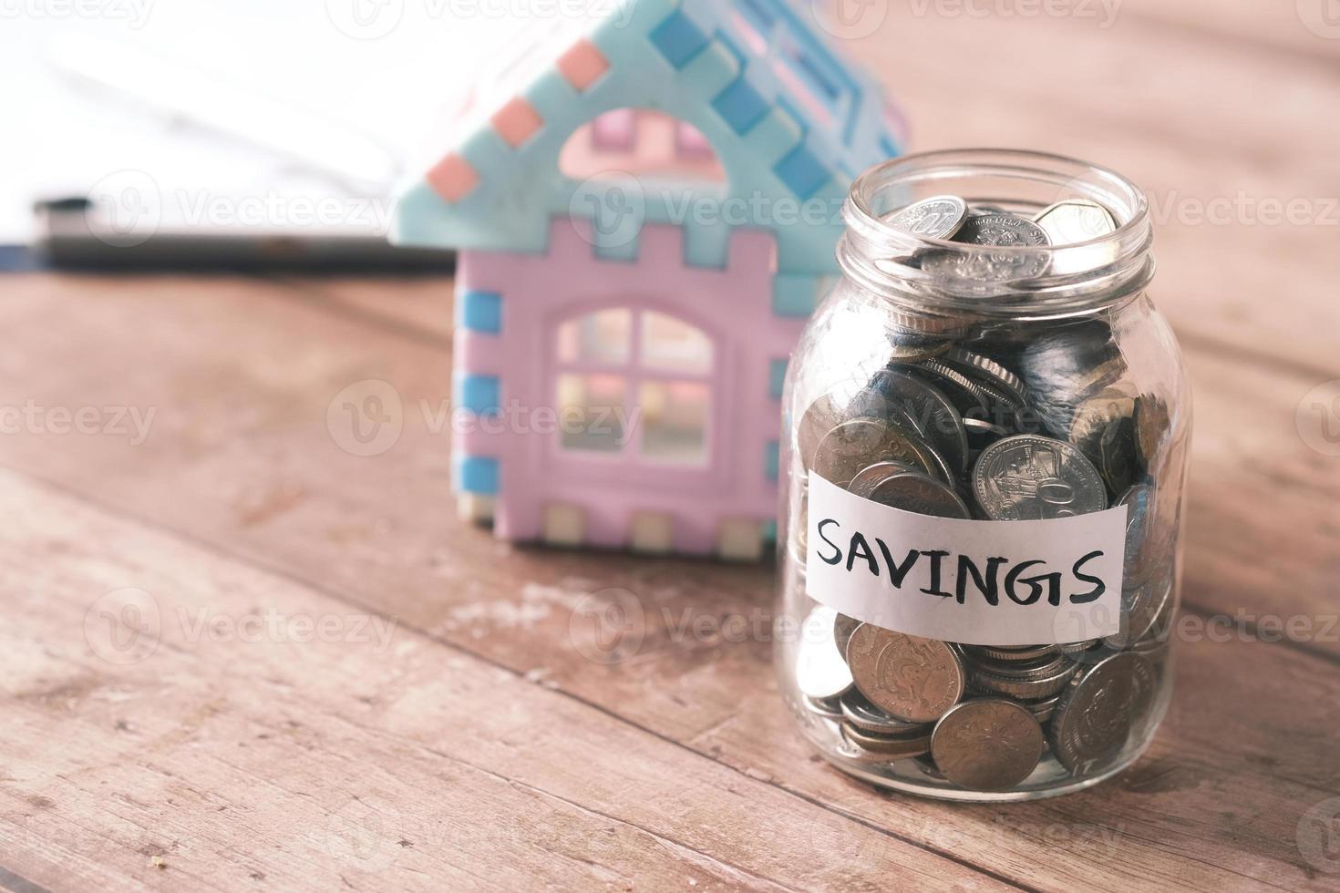 house finance concept with house model and saving coin jar on table photo