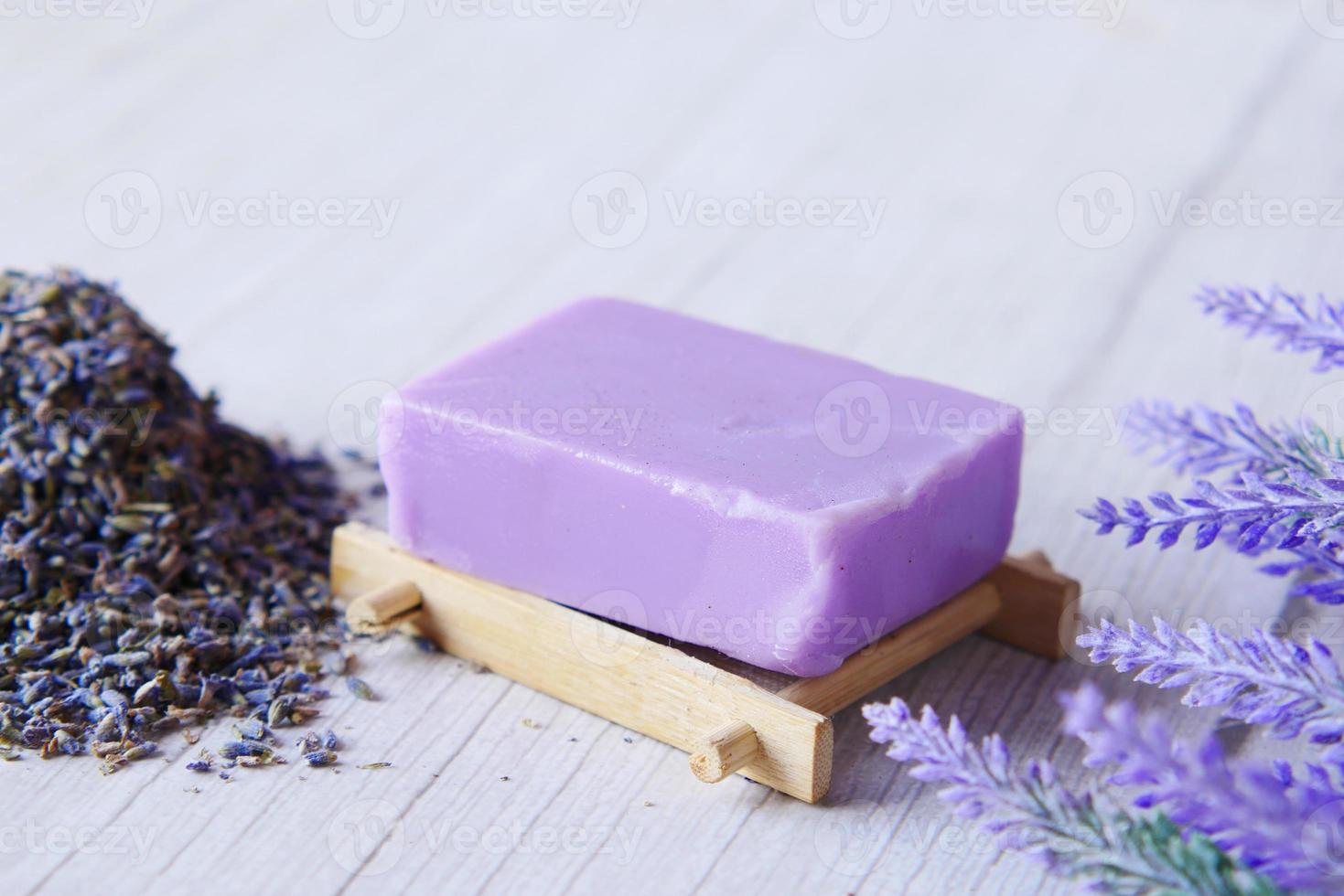 Barra de jabón natural casero y flor de lavanda sobre fondo púrpura foto