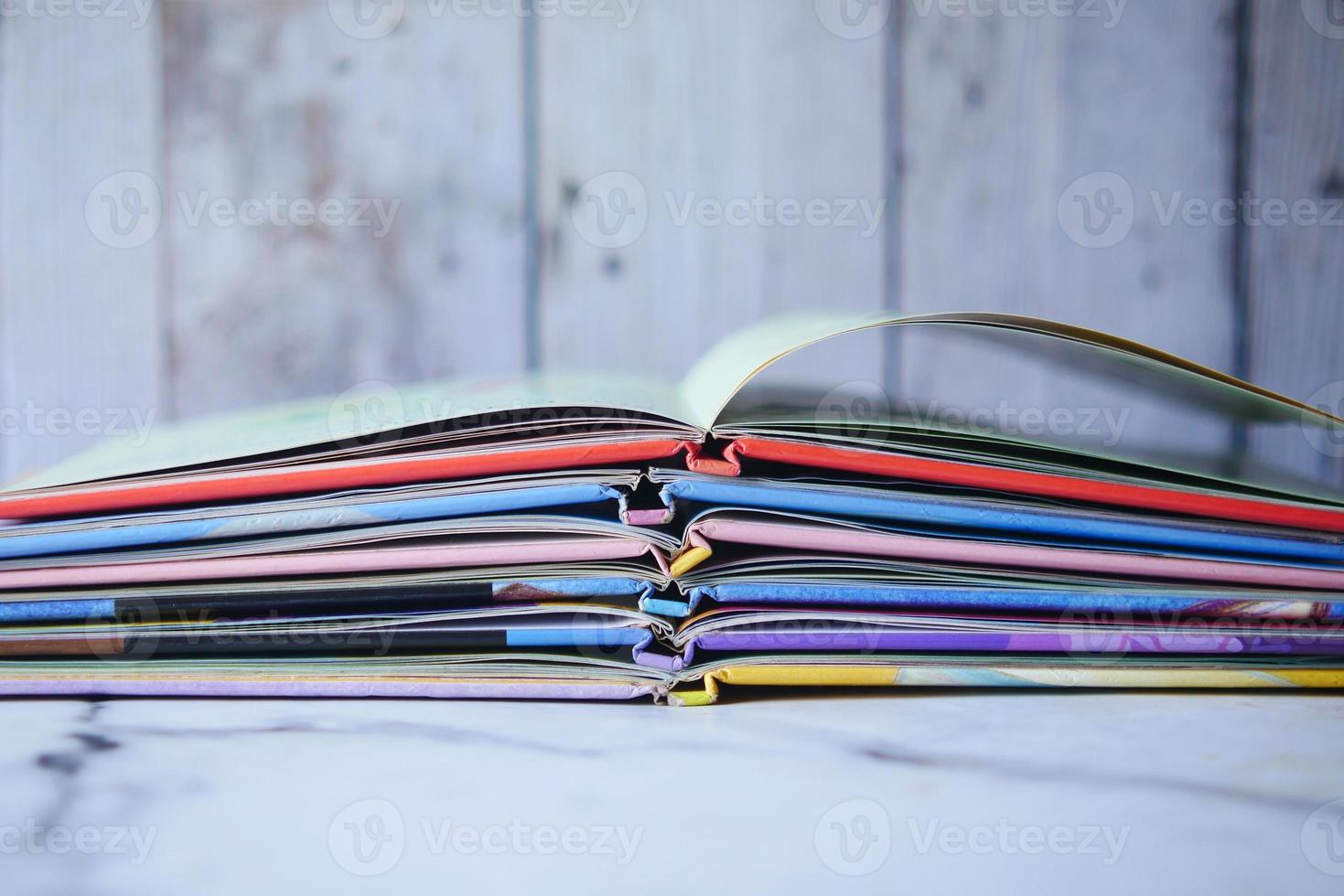 stack of color open book on table photo
