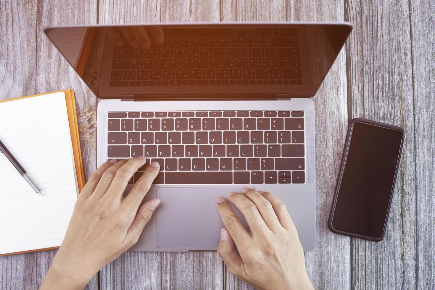 top view of man hand using laptop and smart phone working remotely at home. photo