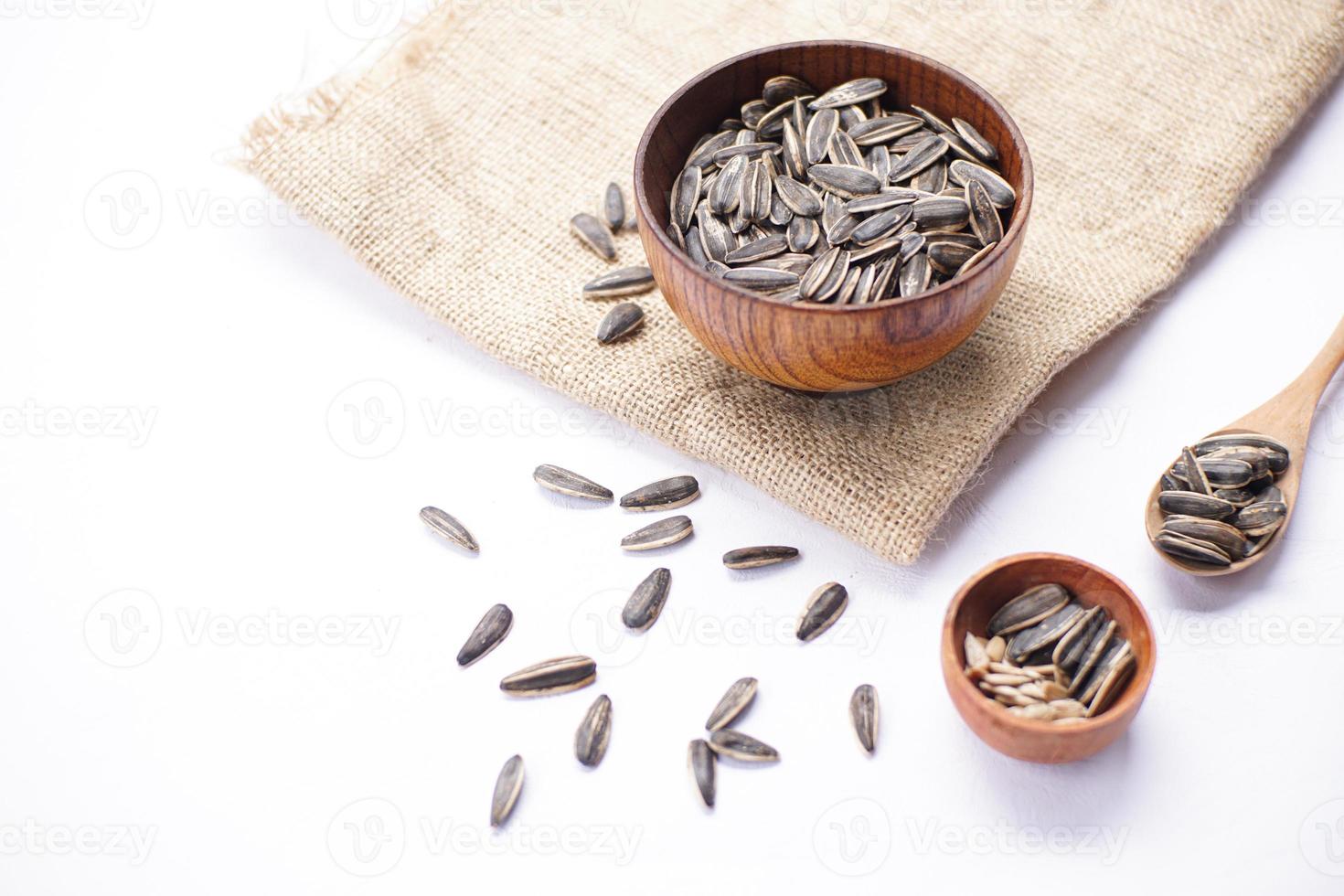 Sunflower seeds in a wooden bowl on a white table photo