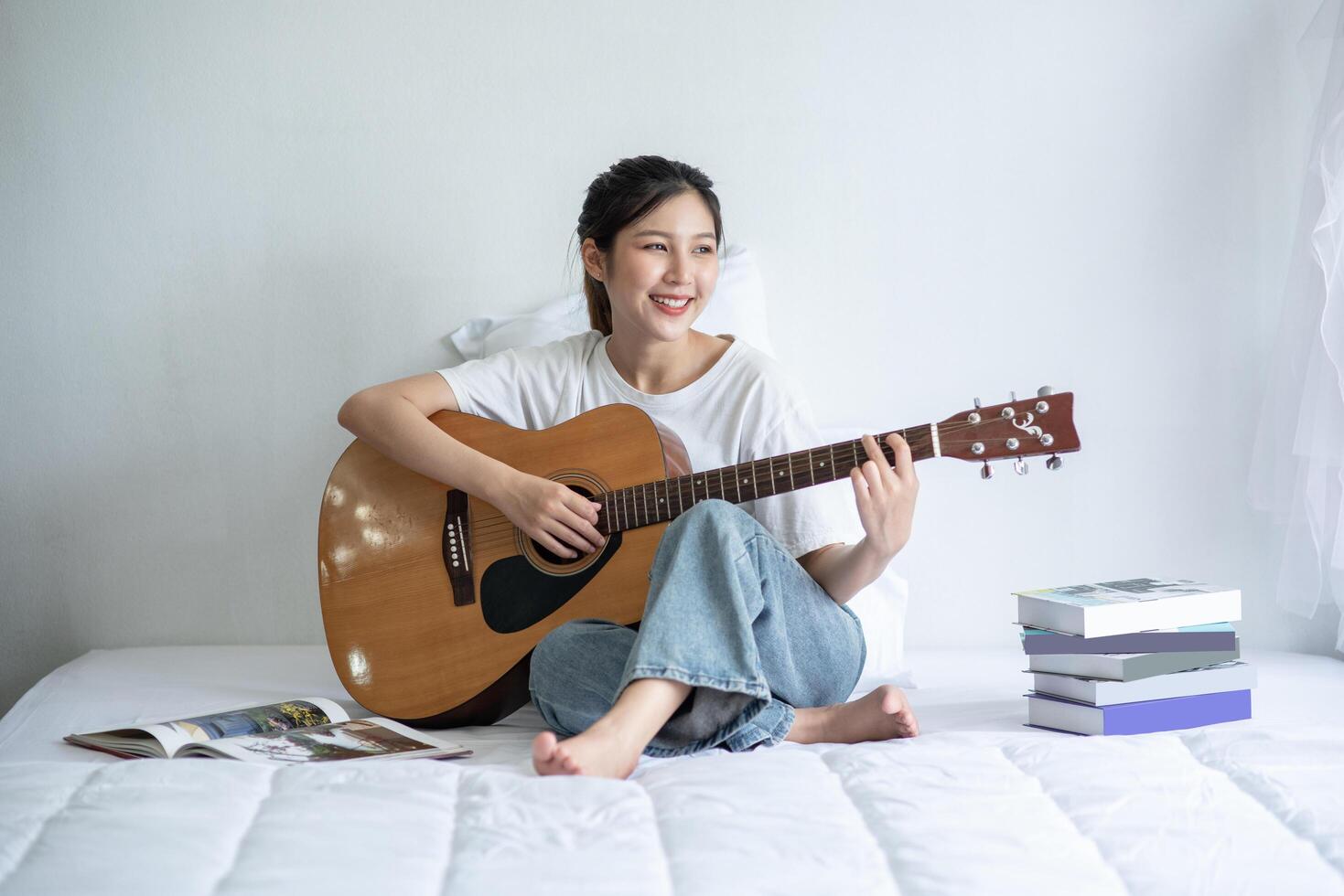 la niña se sentó y tocó la guitarra en la cama. foto