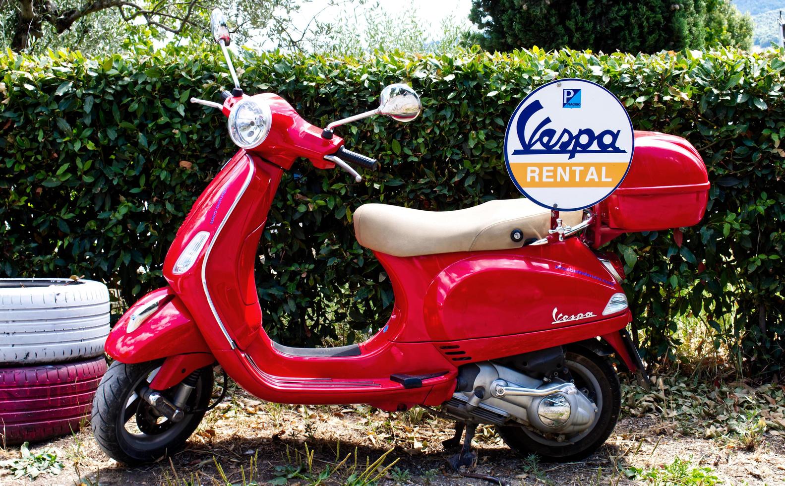 Florence, Italy, 2019 - Flaming red vintage Vespa scooter parked for rent. Italy photo