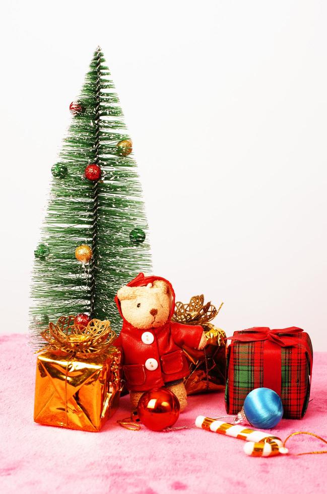 muñeco de peluche y caja de regalo con fondos de decoración de árboles de navidad foto