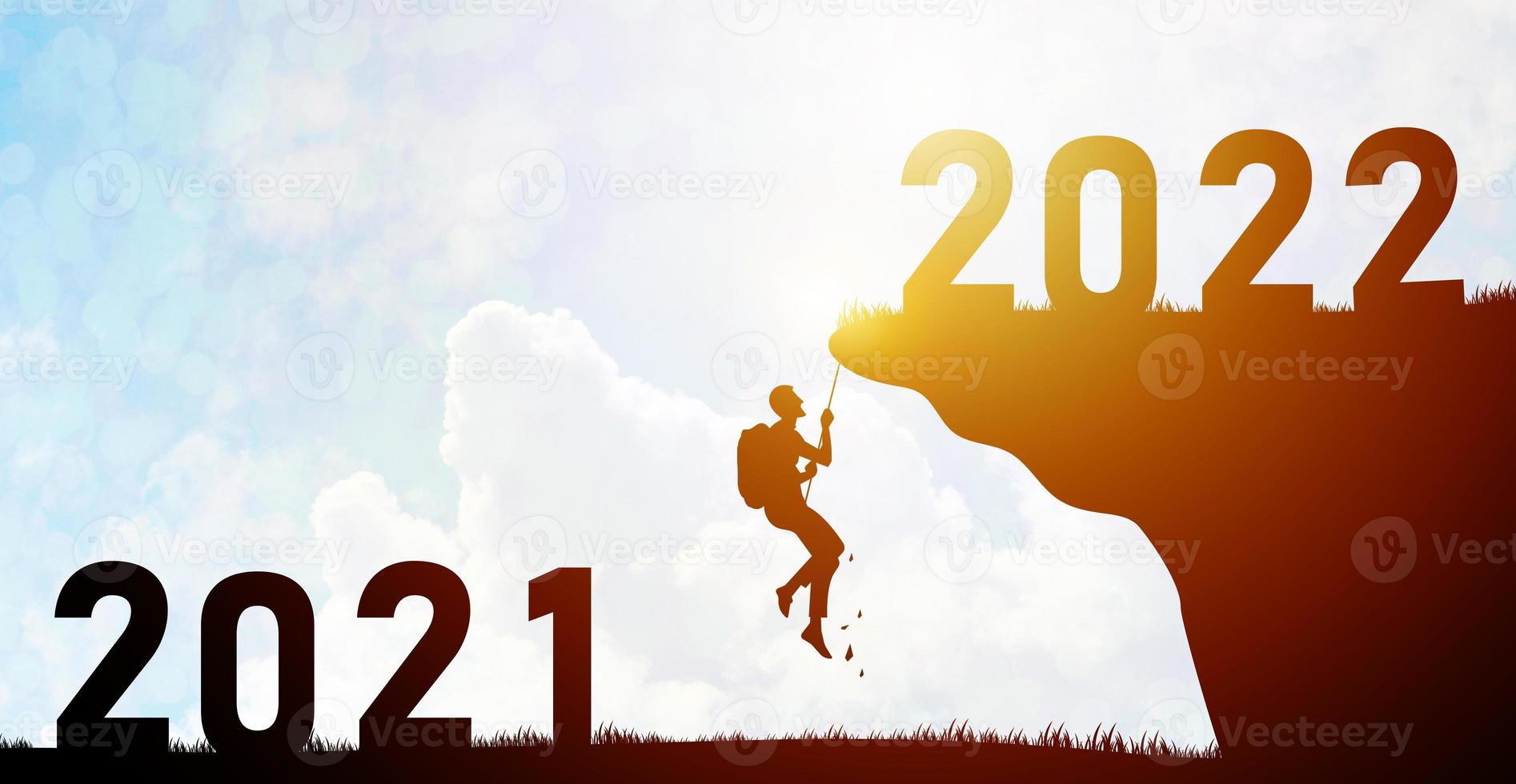 The silhouette man tried to climb the mountain in order to reach his goal. Between the numbers 2021 and 2022 with the intention and ready to start over in the future adventure to reach the goal photo
