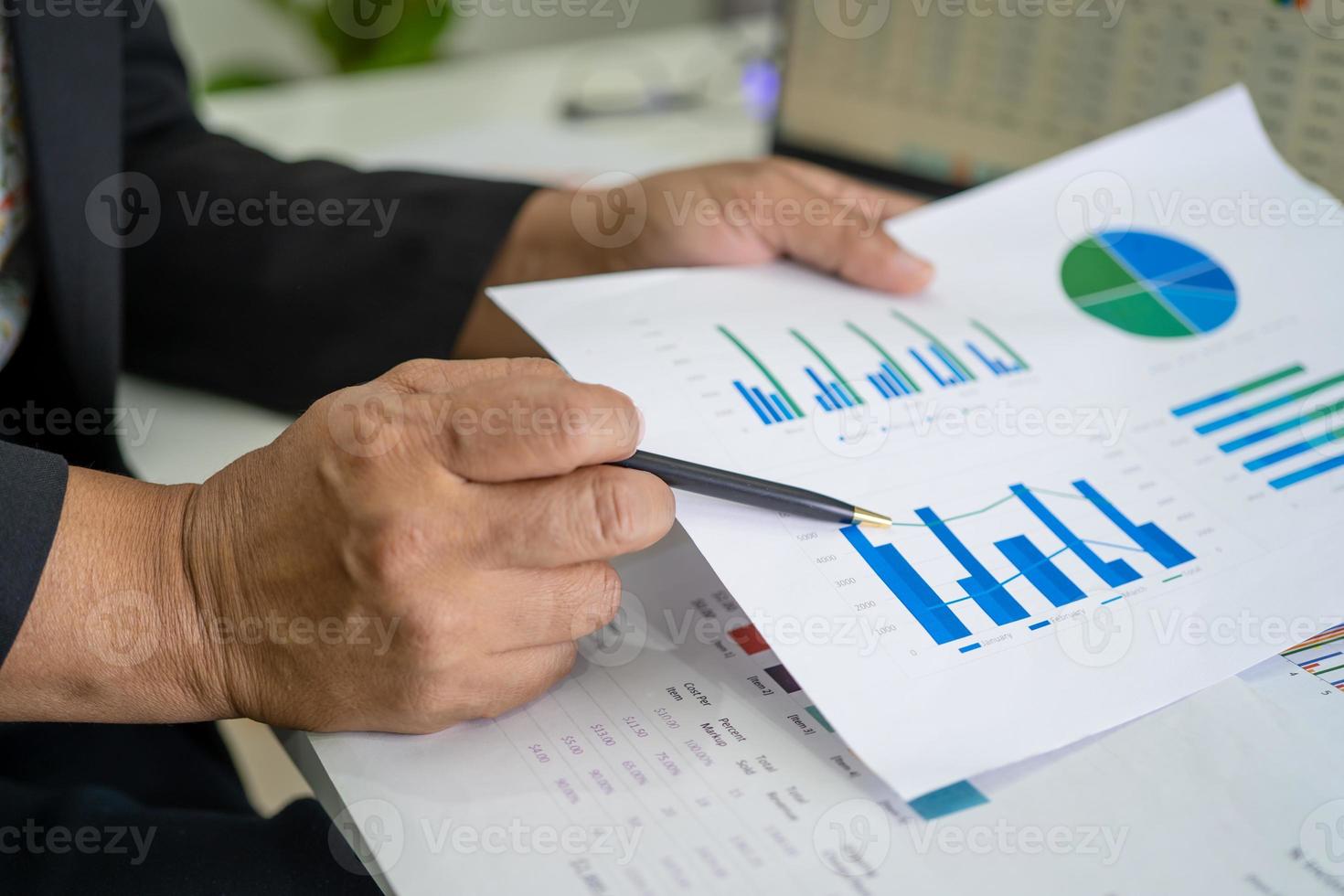 Asian accountant working and analyzing financial reports project accounting with chart graph and calculator in modern office, finance and business concept. photo
