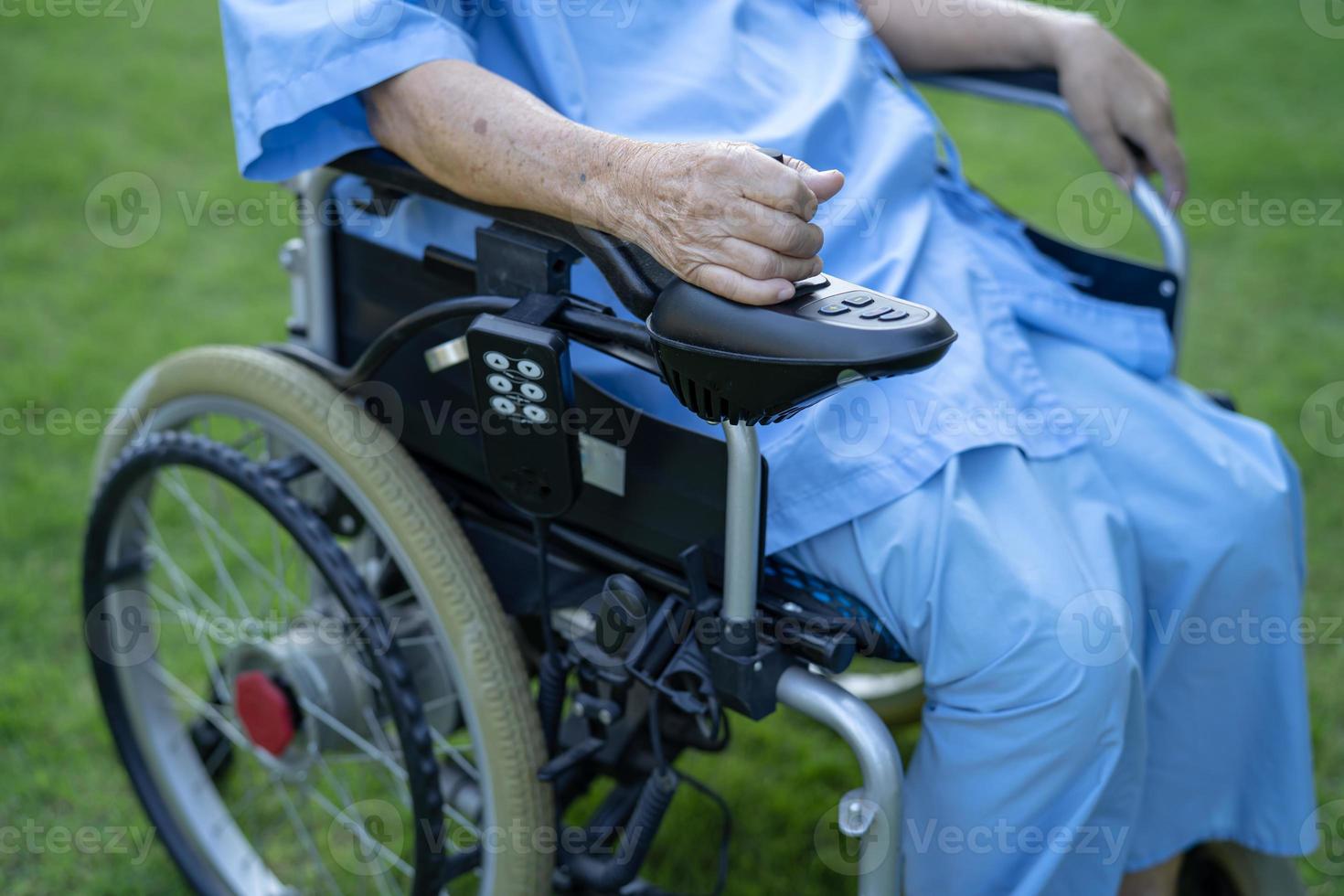 Paciente asiático mayor o anciano en silla de ruedas eléctrica con control remoto en la sala del hospital de enfermería, concepto médico fuerte y saludable foto