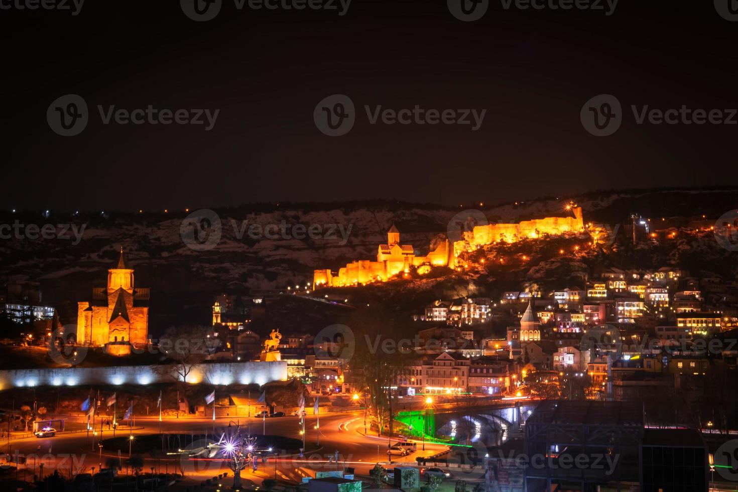 Panoramic night view old Tbilisi with snowy mountains and Illuminated city sreets photo