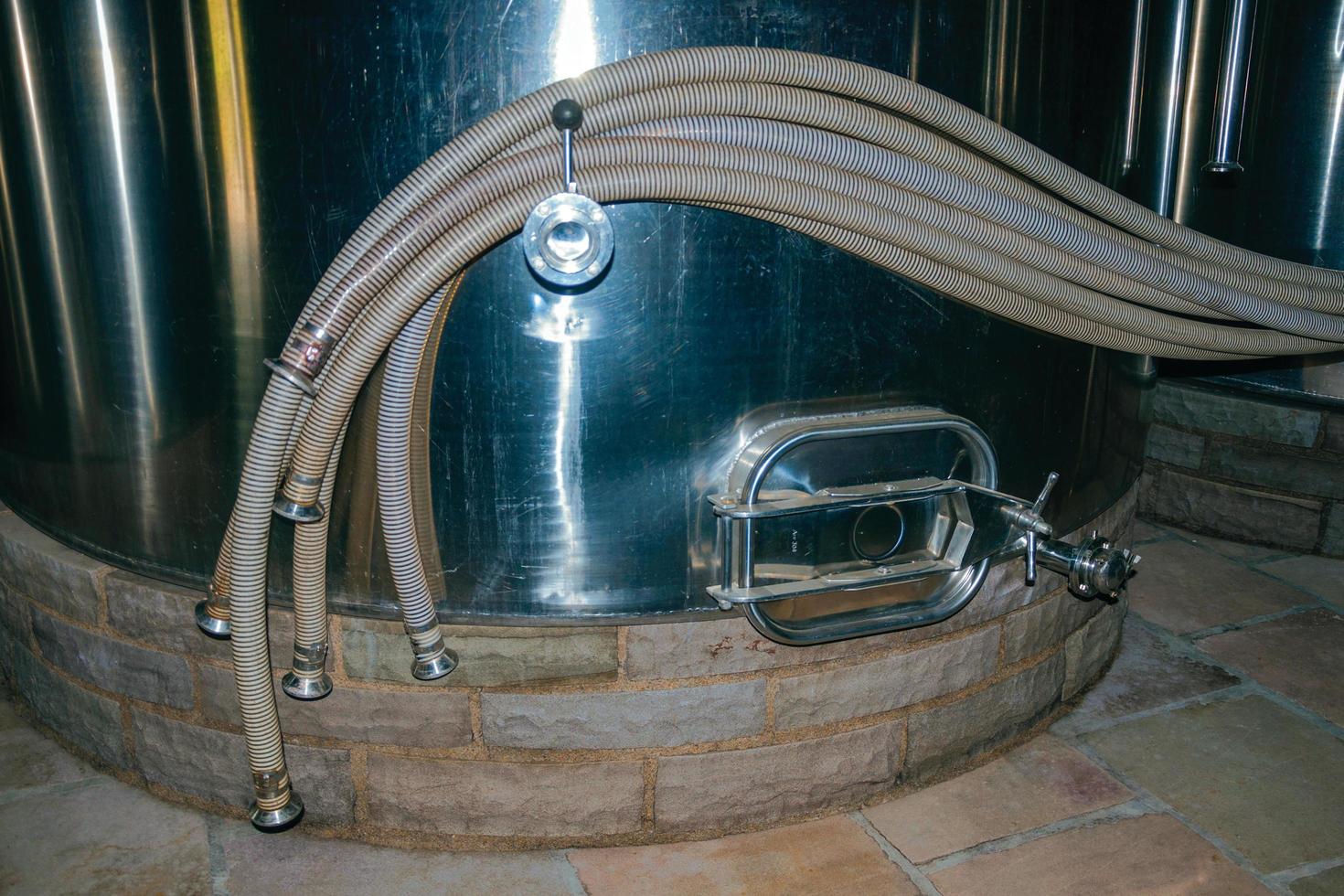 Bento Goncalves, Brazil - July 13, 2019. Stainless steel storage tank for wine with pipes and hatch in a winery plant near Bento Goncalves. A friendly country town famous for its wine production. photo