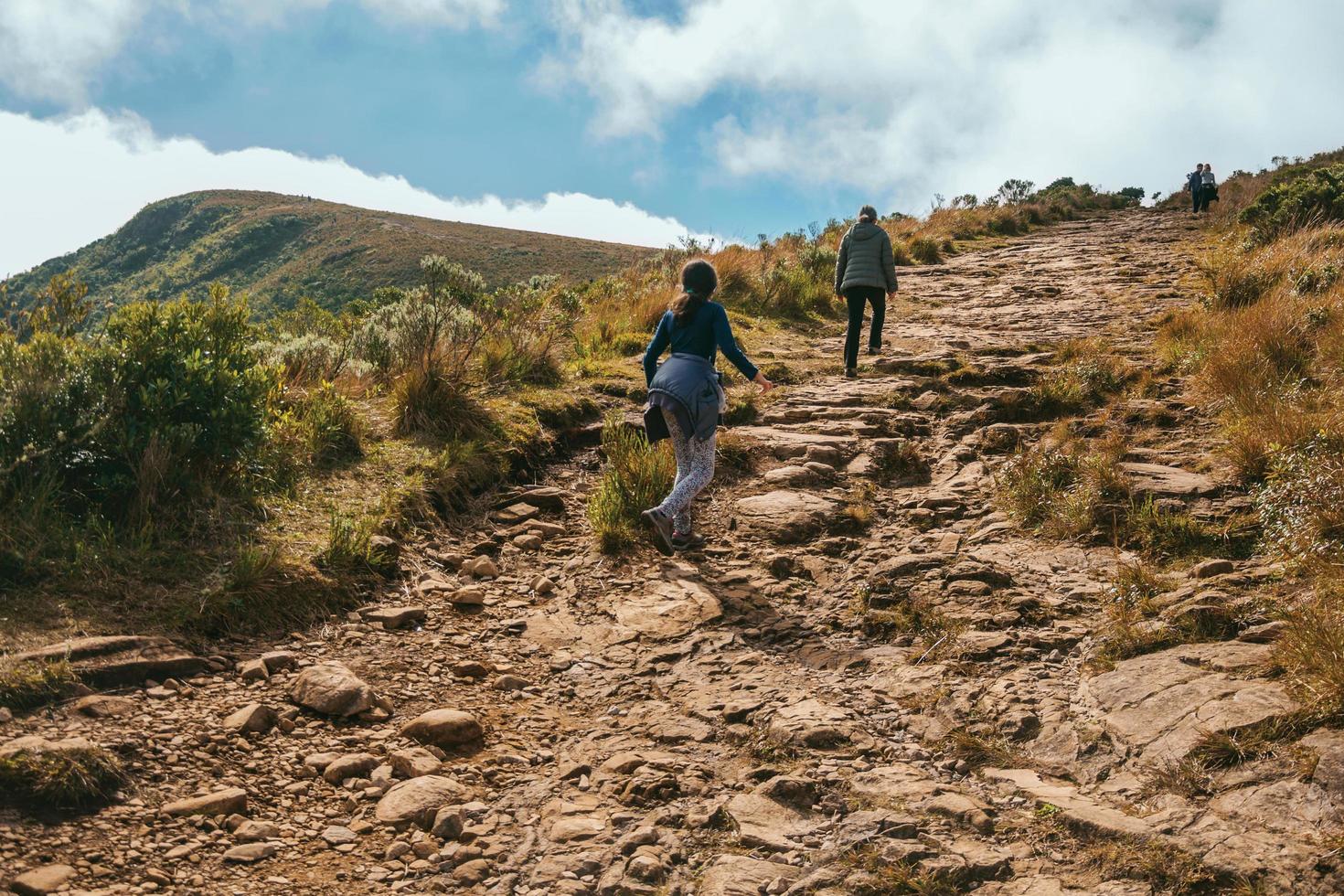 Cambara do Sul - Brazil, July 18, 2019. People on rocky trail going up to the top of Fortaleza Canyon in a sunny day near Cambara do Sul. A small rural town with amazing natural tourist attractions. photo