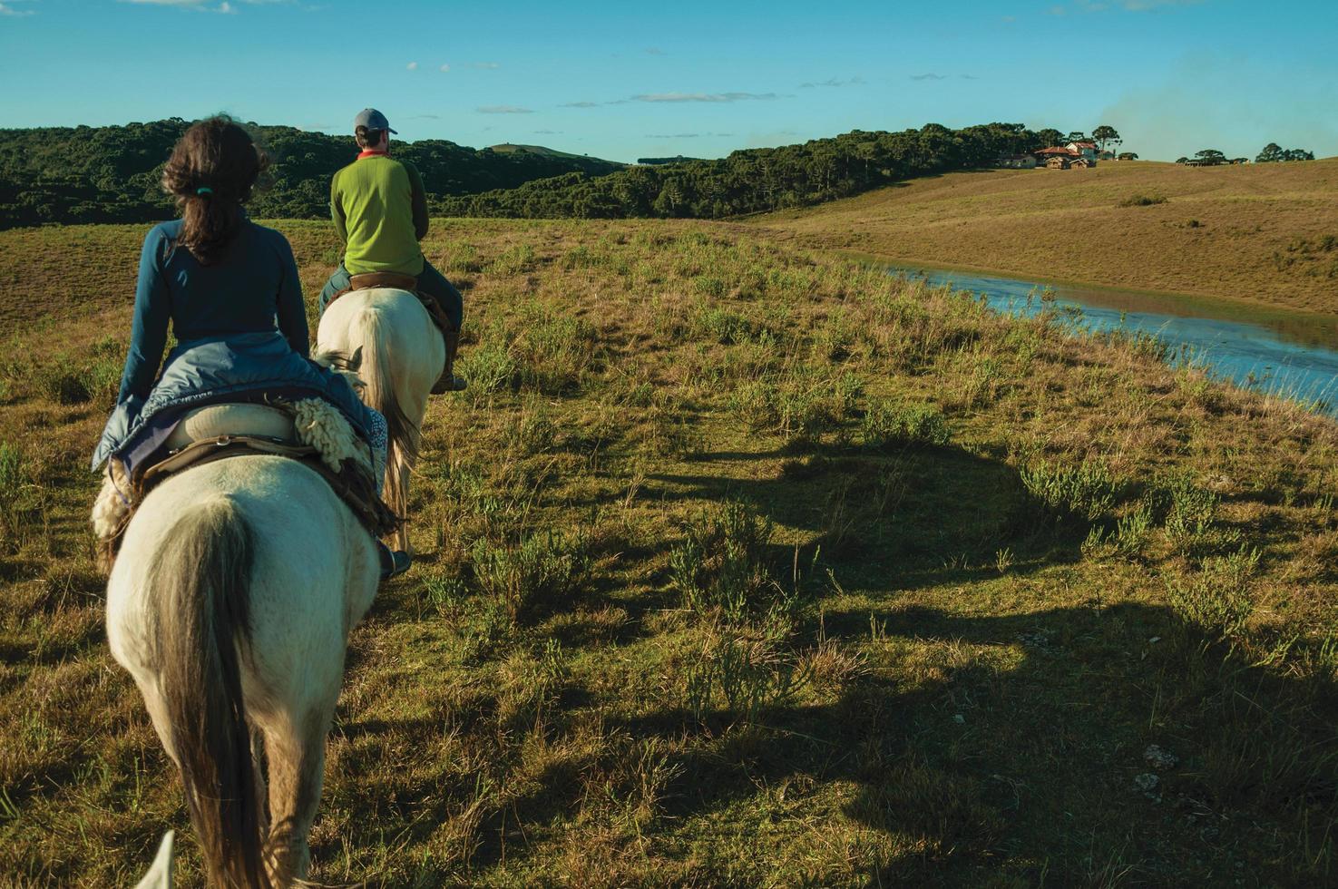 Cambara do Sul, Brazil - July 18, 2019. Girl and man riding horse in a landscape of rural lowlands called Pampas at sunset near Cambara do Sul. A rural town with amazing natural tourist attractions. photo