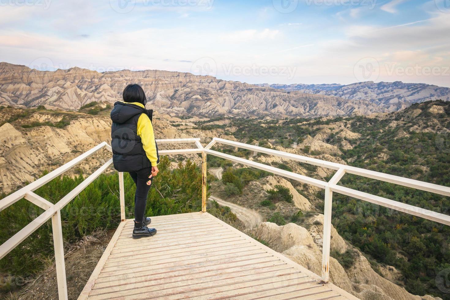 Brunette woman stands on the platform viewpoint and looks over beautiful landscape of Vashlovani nature reserve photo