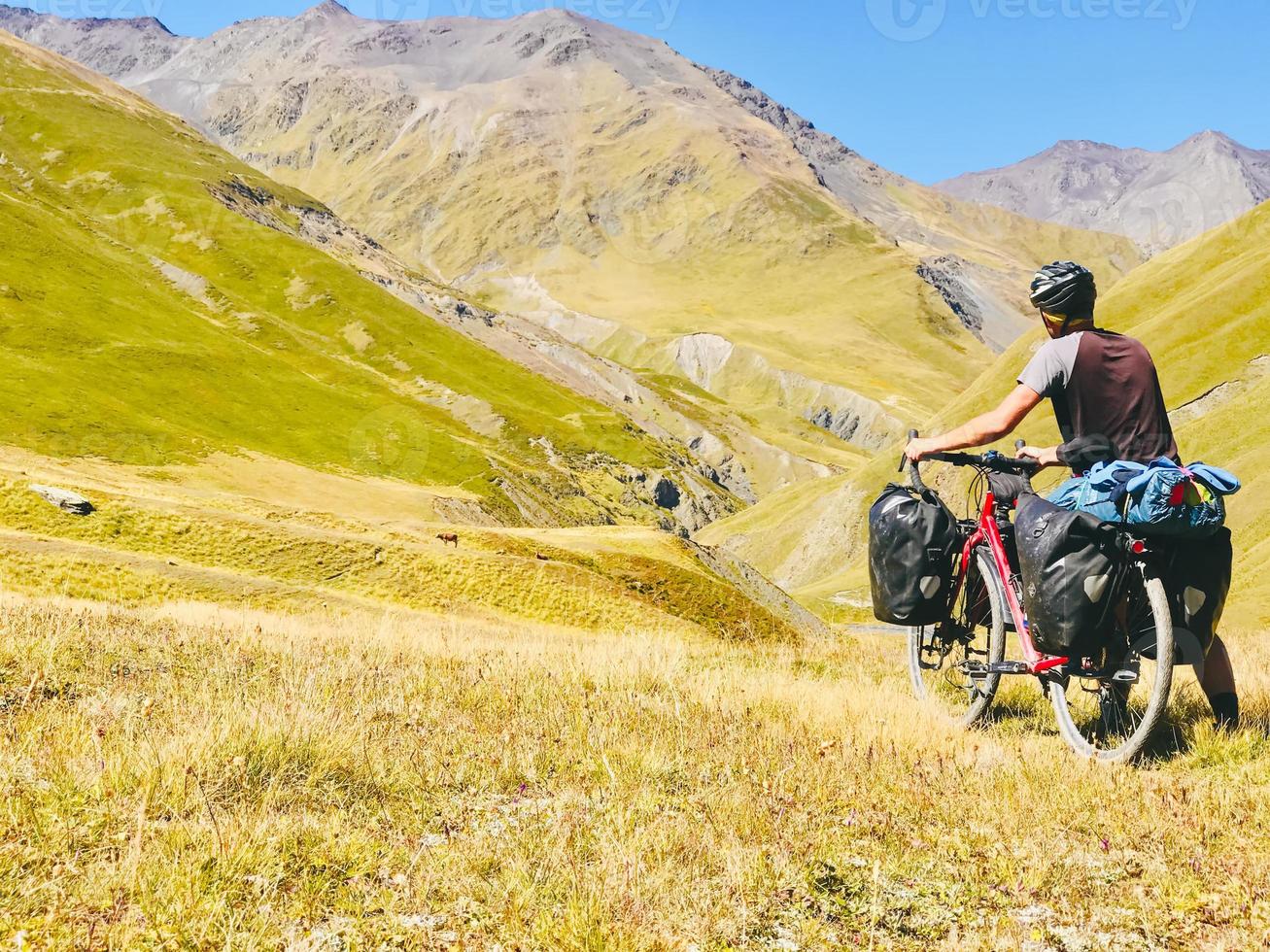 Back view cyclist push touring bicycle uphill to mountain. Atsunta pass trekking route on bicycle photo