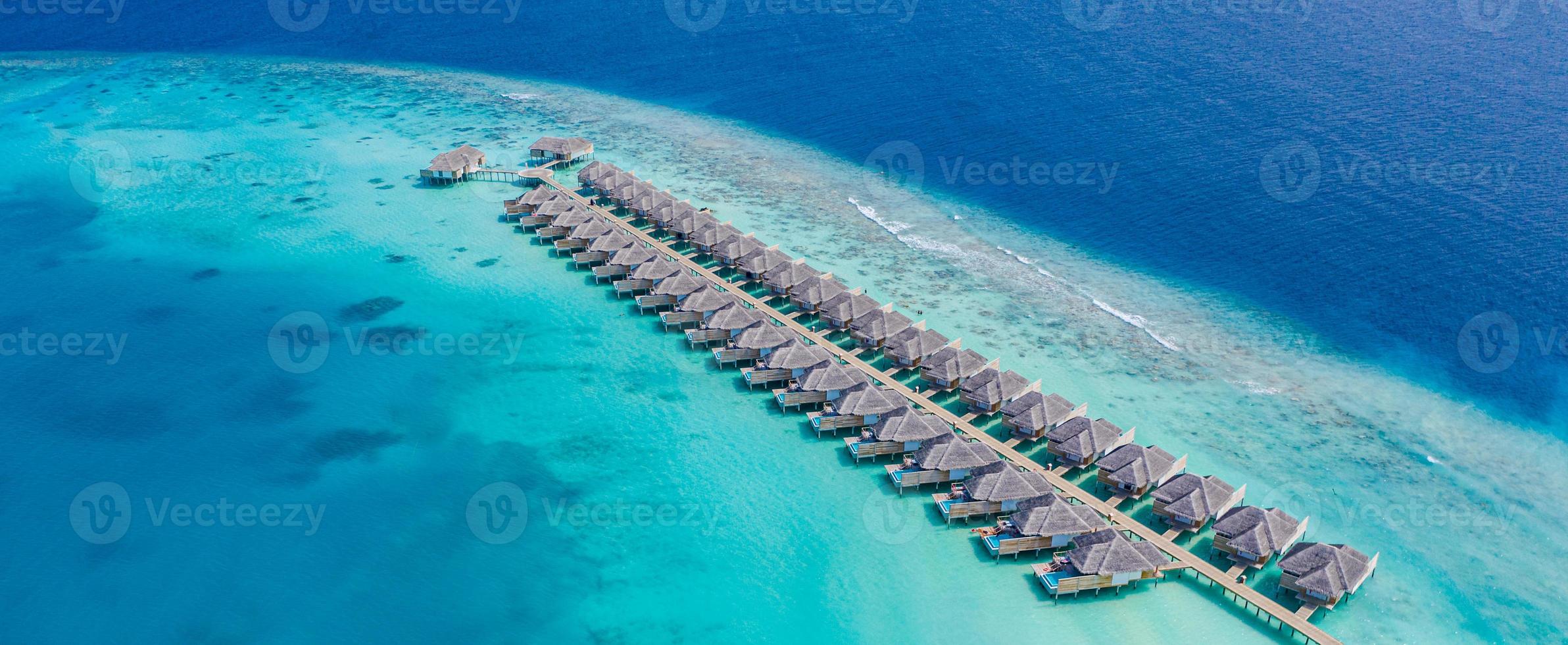 Perfect aerial landscape, luxury tropical resort or hotel with water villas and beautiful beach scenery. Amazing bird eyes view in Maldives, landscape seascape aerial view over a Maldives photo