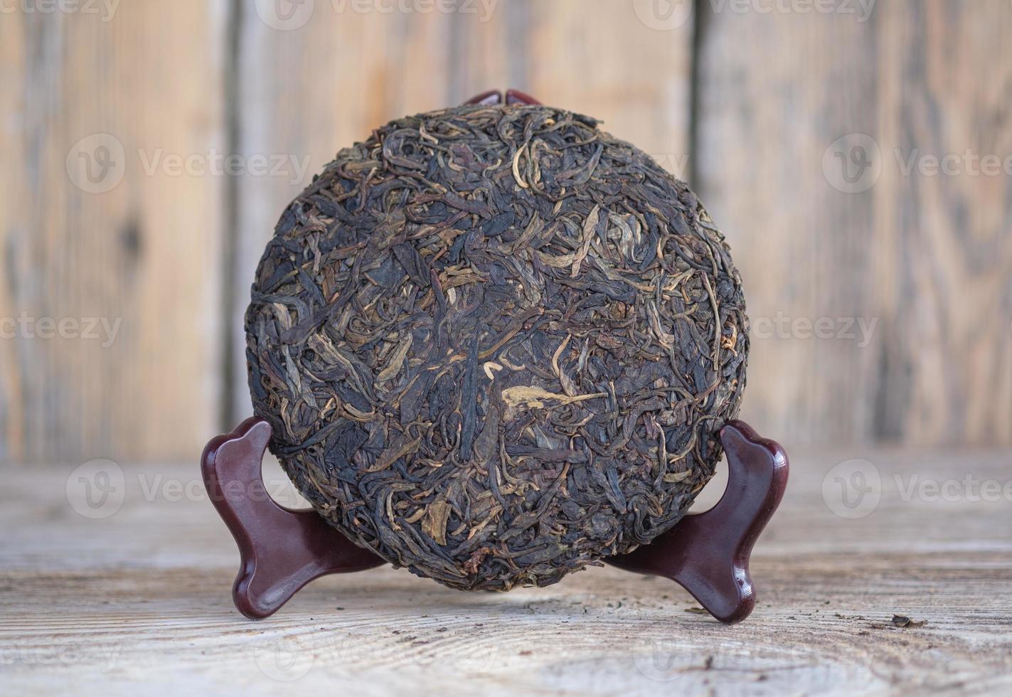 Té pu-erh chino tradicional sobre un soporte de madera. té fermentado crudo en forma de panqueque foto