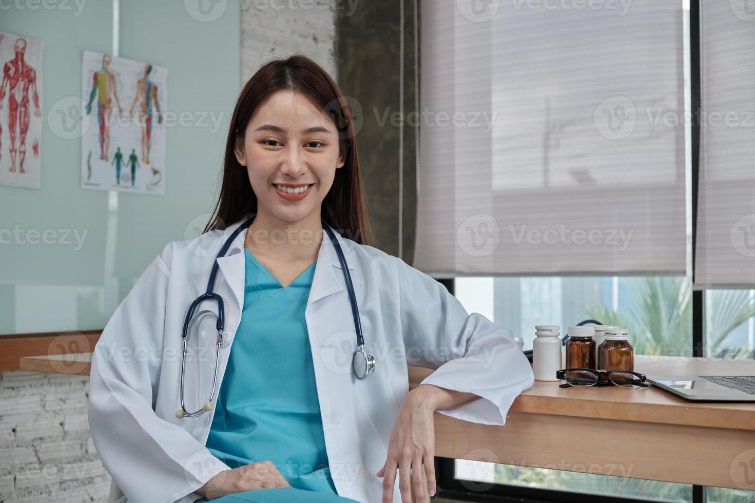 Retrato de hermosa doctora de etnia asiática en uniforme con estetoscopio, sonriendo y mirando a la cámara en la clínica del hospital. una persona que tenga experiencia en tratamiento profesional. foto